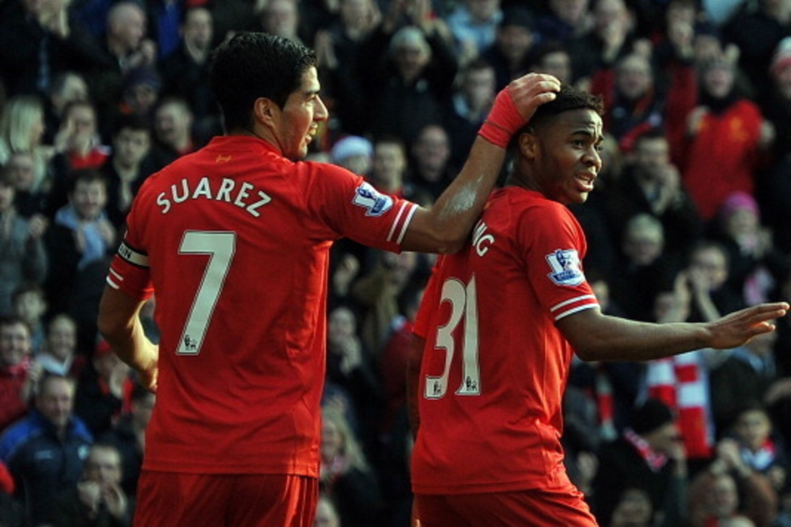 Liverpool's Uruguayan striker Luis Suarez (L) celebrates setting up Liverpool's English midfielder Raheem Sterling (R) to score their team's second goal during the English Premier League football match between Liverpool and Cardiff City at Anfield stadium