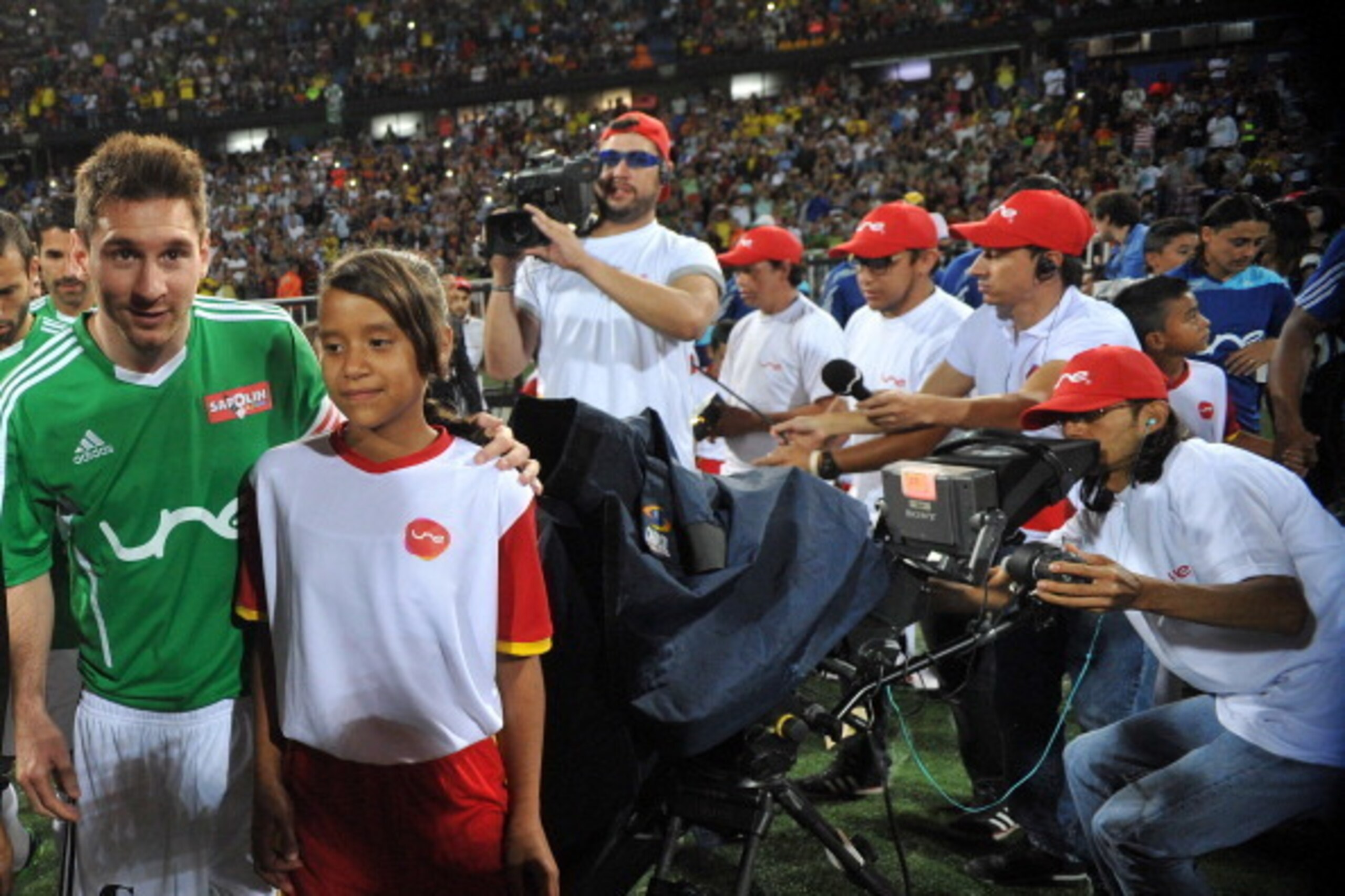 MEDELLIN, COLOMBIA - JUNE 29:  Lionel Messi of Messi & Friends (L) walks on the pitch accompanied by a young female matchday mascot before the start of the Messi & Friends v The Rest of the World XI charity soccer match at the Atanasio Giradot Stadium on 