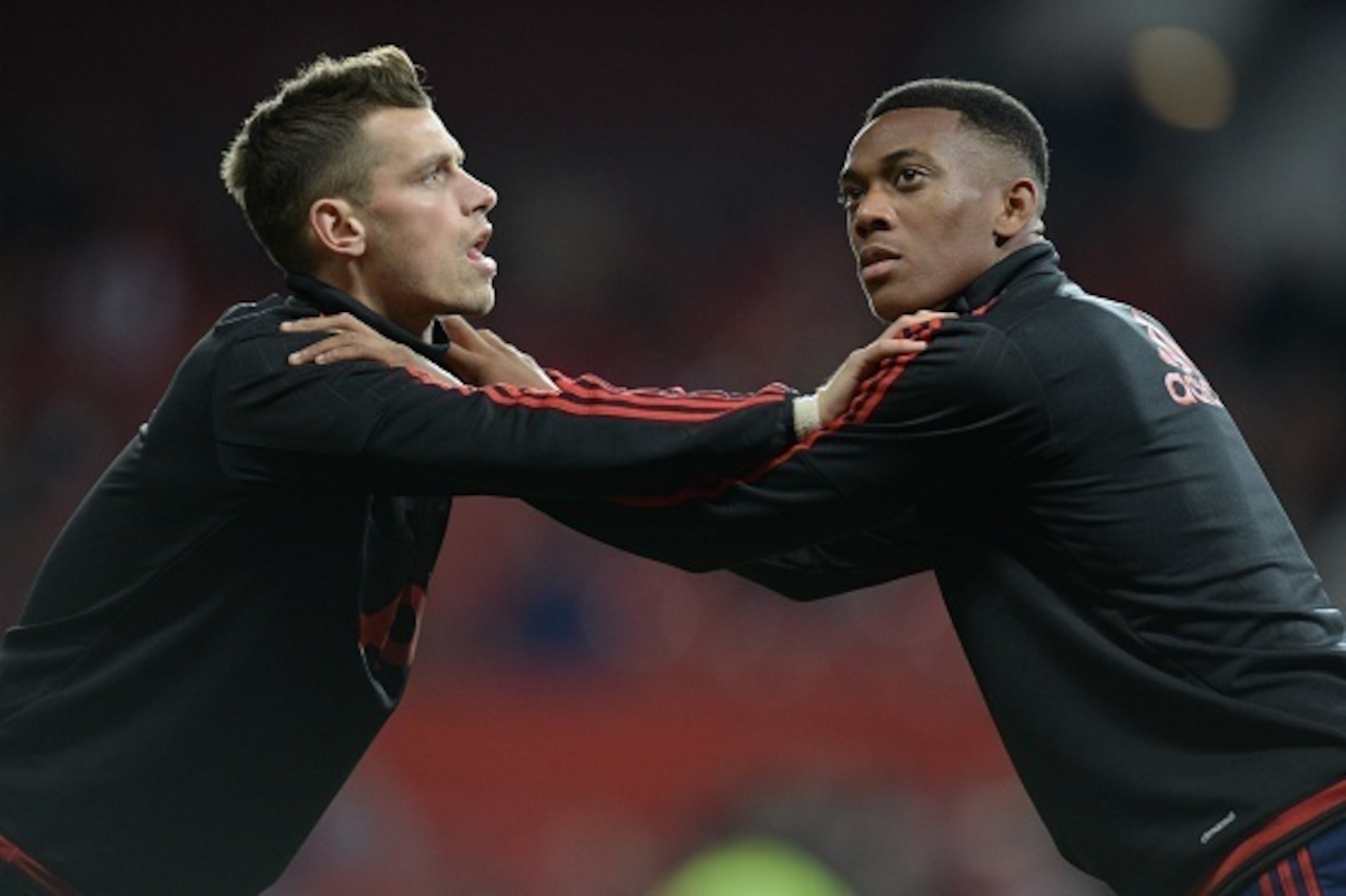 Manchester United's French midfielder Anthony Martial warms up with Manchester United's French midfielder Morgan Schneiderlin (L) ahead of the English League Cup third round football match between Manchester United and Ipswich Town at Old Trafford in Manc