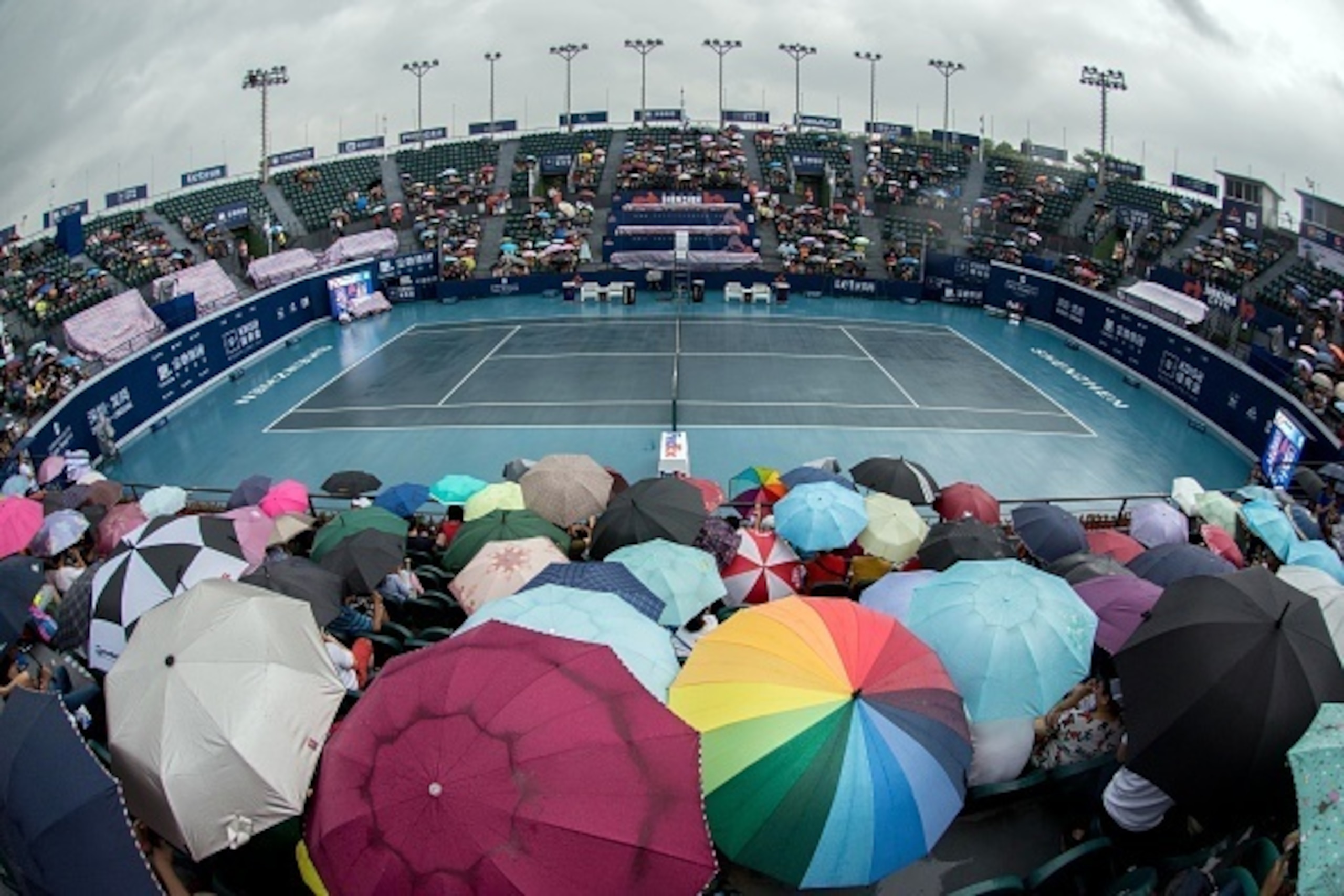 Tennis fans wait in the rain prior to the men's singles semi-final matches at the Shenzhen Open tennis tournament in Shenzhen, southern China's Guangdong province on October 3, 2015. Tomas Berdych and Marin Cilic endured a frustrating wait on October 3 as