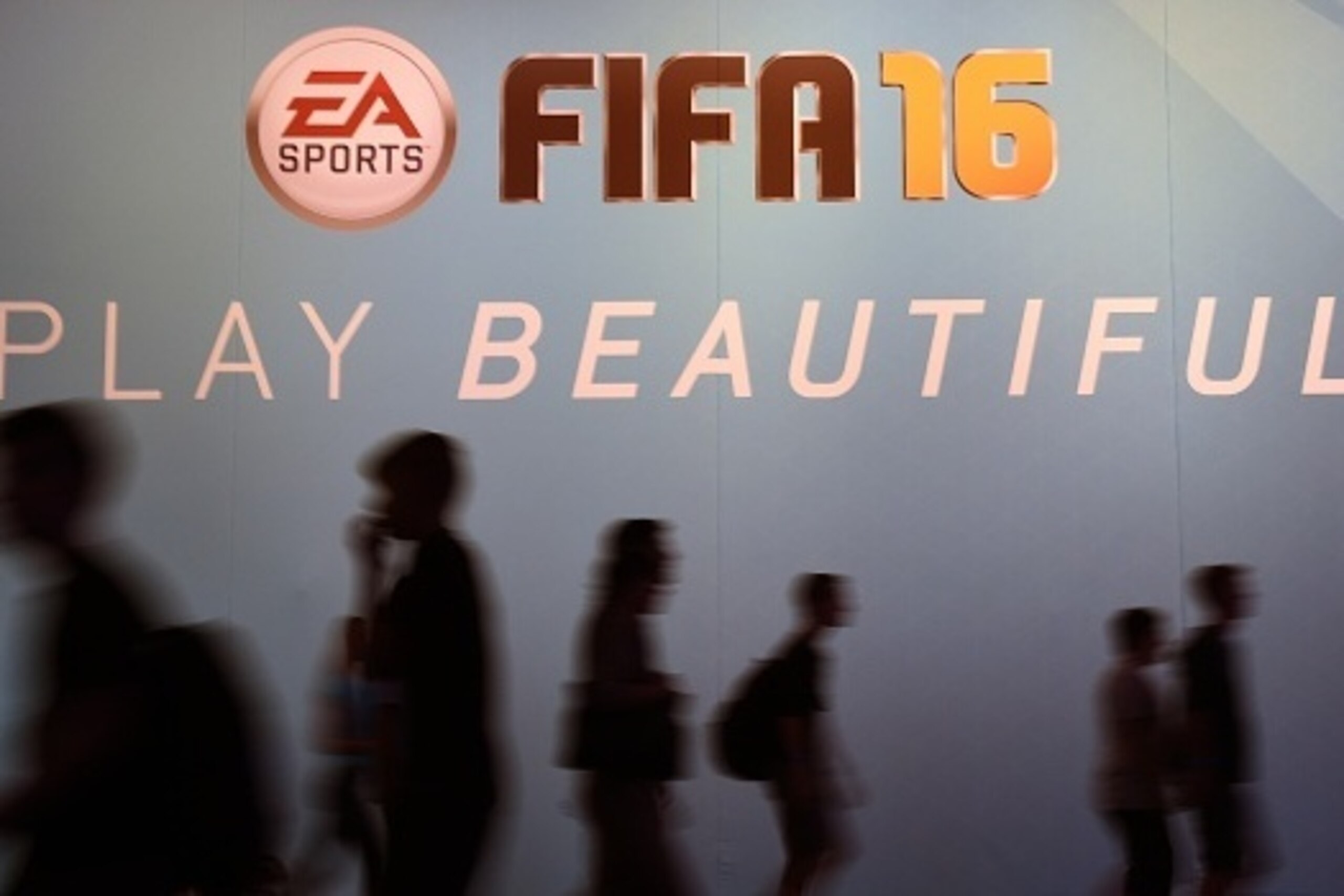 Visitors walk past an ad for the FIFA 16 football game at the Gamescom fair in Cologne, western Germany on August 7, 2015. The trade fair for interactive games is running until August 9, 2014. PHOTO / PATRIK STOLLARZ        (Photo credit should read PATRI