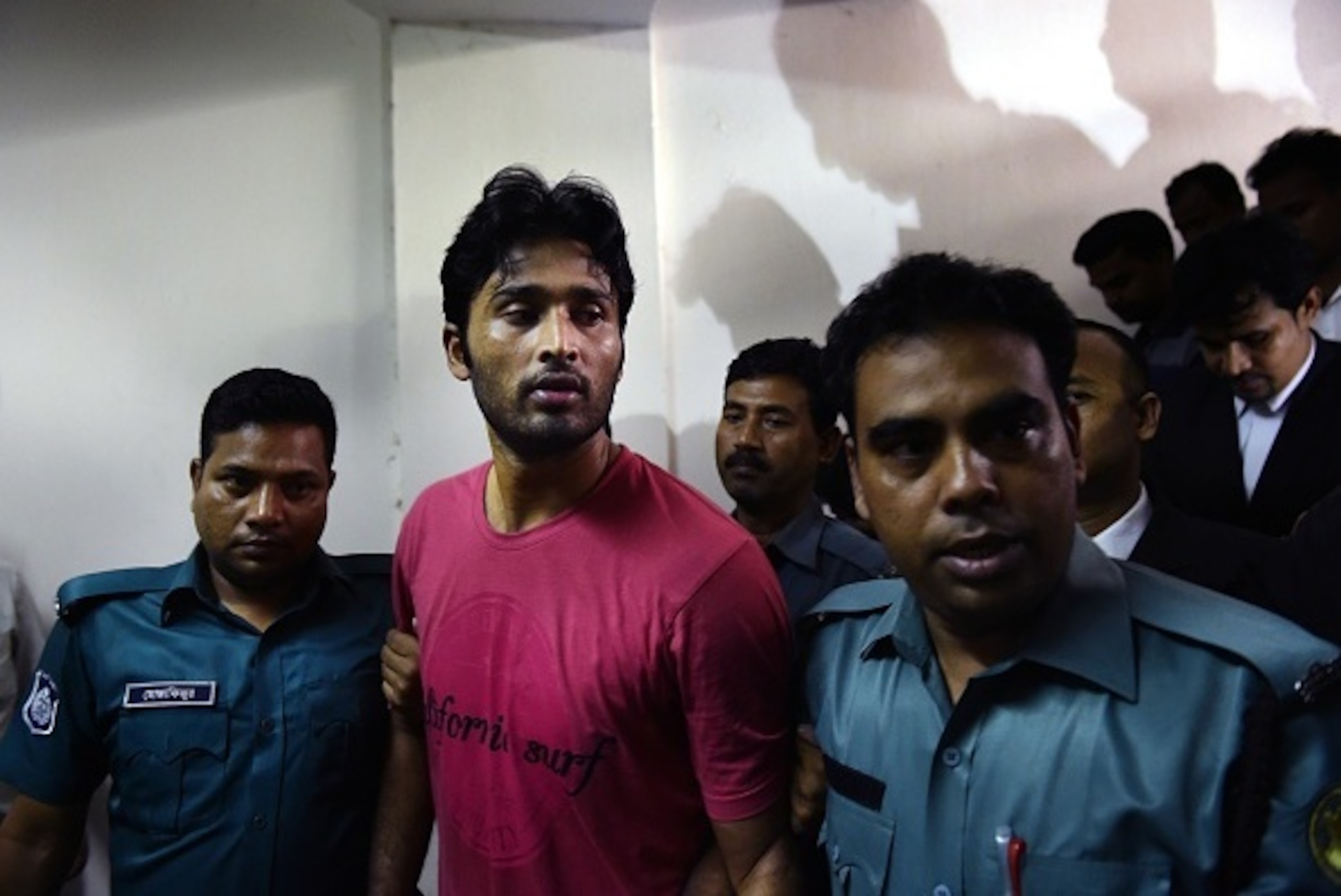 Bangladeshi security personnel escort fugitive cricketer Shahadat Hossain (C) after he surrendered in Dhaka on October 5, 2015. Hossain was remanded in jail on October 5 shortly after he surrendered to a court over allegations of beating his 11-year-old m