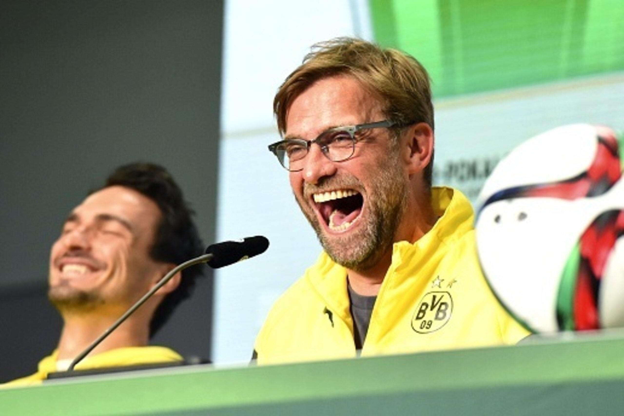Head coach of German Bundesliga football club Borussia Dortmund, Juergen Klopp (R), laughs during a press conference on the eve of the German DFB Cup Final 2015 match Borussia Dortmund vs VfL Wolfsburg on May 29, 2015, in Berlin, Germany, next to Dortmund