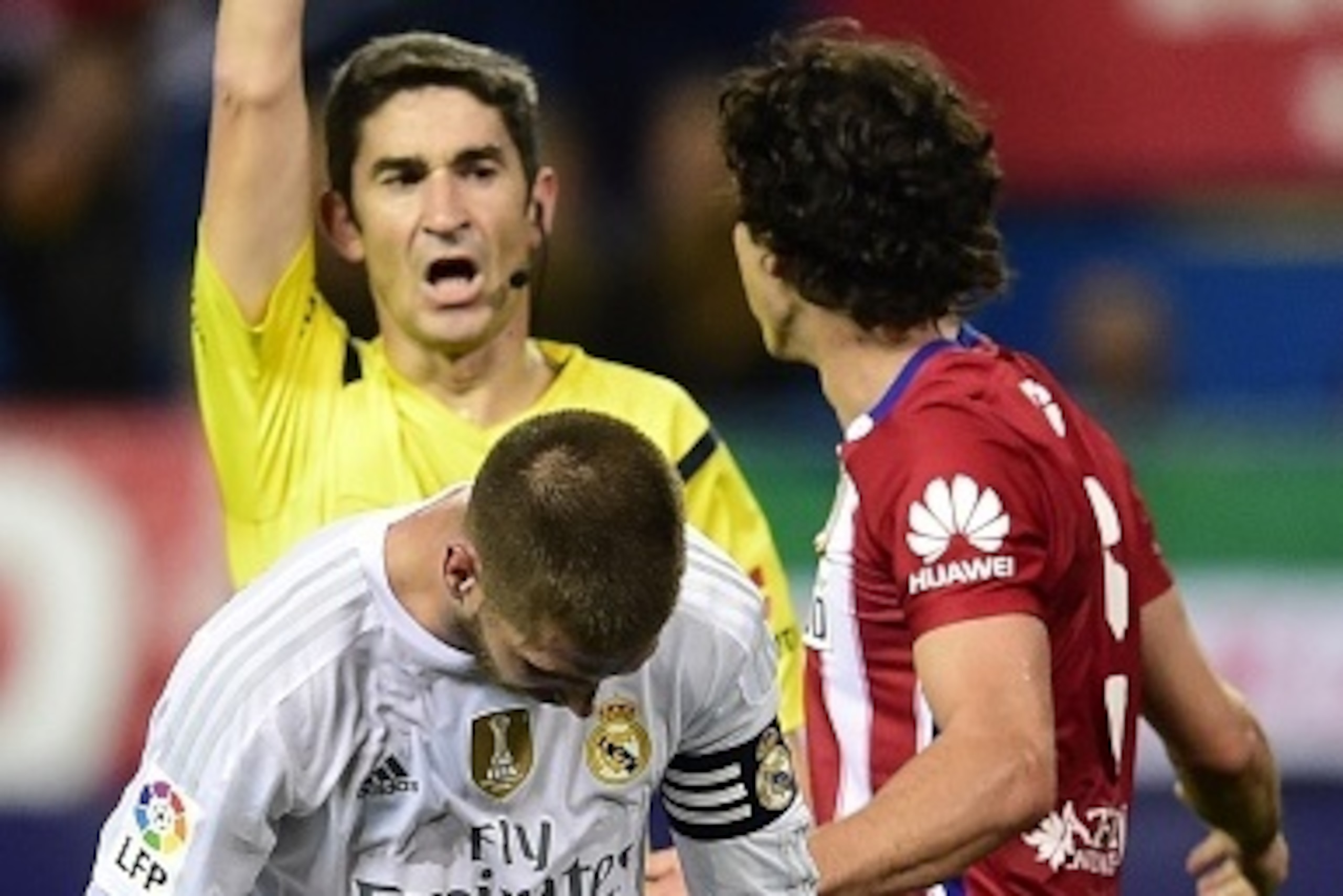 Real Madrid's defender Sergio Ramos (FrontL) is shown a yellow card during the Spanish league football match Club Atletico de Madrid vs Real Madrid CF at the Vicente Calderon stadium in Madrid on October 4, 2015.   AFP PHOTO/ JAVIER SORIANO        (Photo 