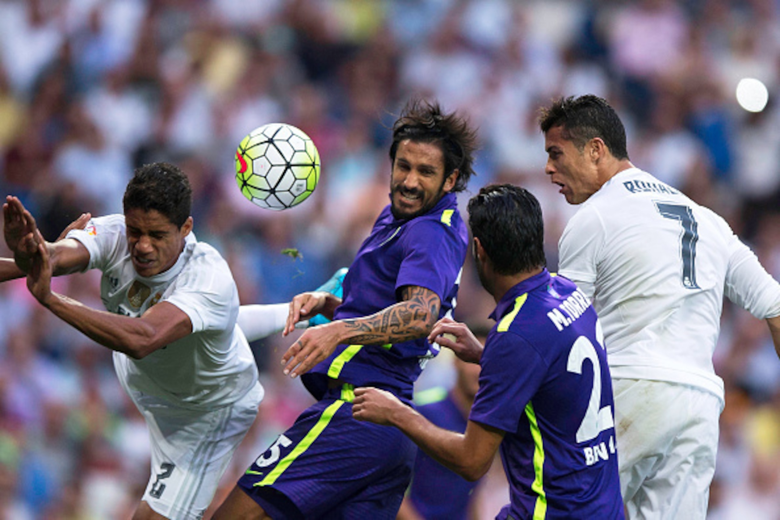 MADRID, SPAIN - SEPTEMBER 26: Cristiano Ronaldo (R) of Real Madrid CF heads the ball behind Miguel Torres (2ndR) and Marcos Angeleri (2ndL), both of Malaga CF and his teammate of Real madrid Raphael Varane (L) during the La Liga match between Real Madrid MADRID, SPAIN - SEPTEMBER 26: Cristiano Ronaldo (R) of Real Madrid CF heads the ball behind Miguel Torres (2ndR) and Marcos Angeleri (2ndL), both of Malaga CF and his teammate of Real madrid Raphael Varane (L) during the La Liga match between Real Madrid