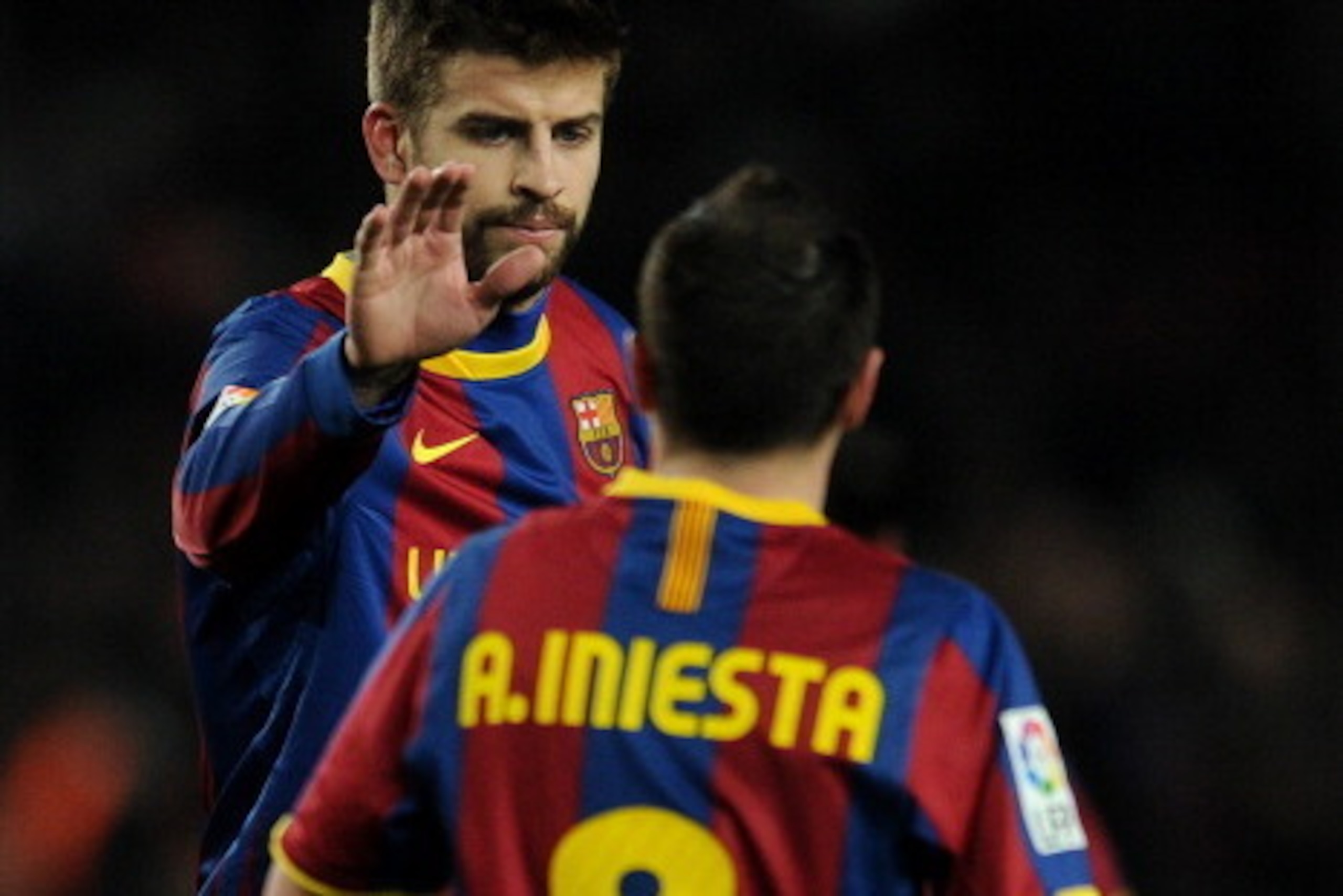 BARCELONA, SPAIN - JANUARY 22:  Gerard Pique (L) of Barcelona congratulates his teammate Andres Iniesta scoring his sides third goal during the la liga match between Barcelona and Racing Santander at the Camp Nou stadium on January 22, 2011 in Barcelona, 