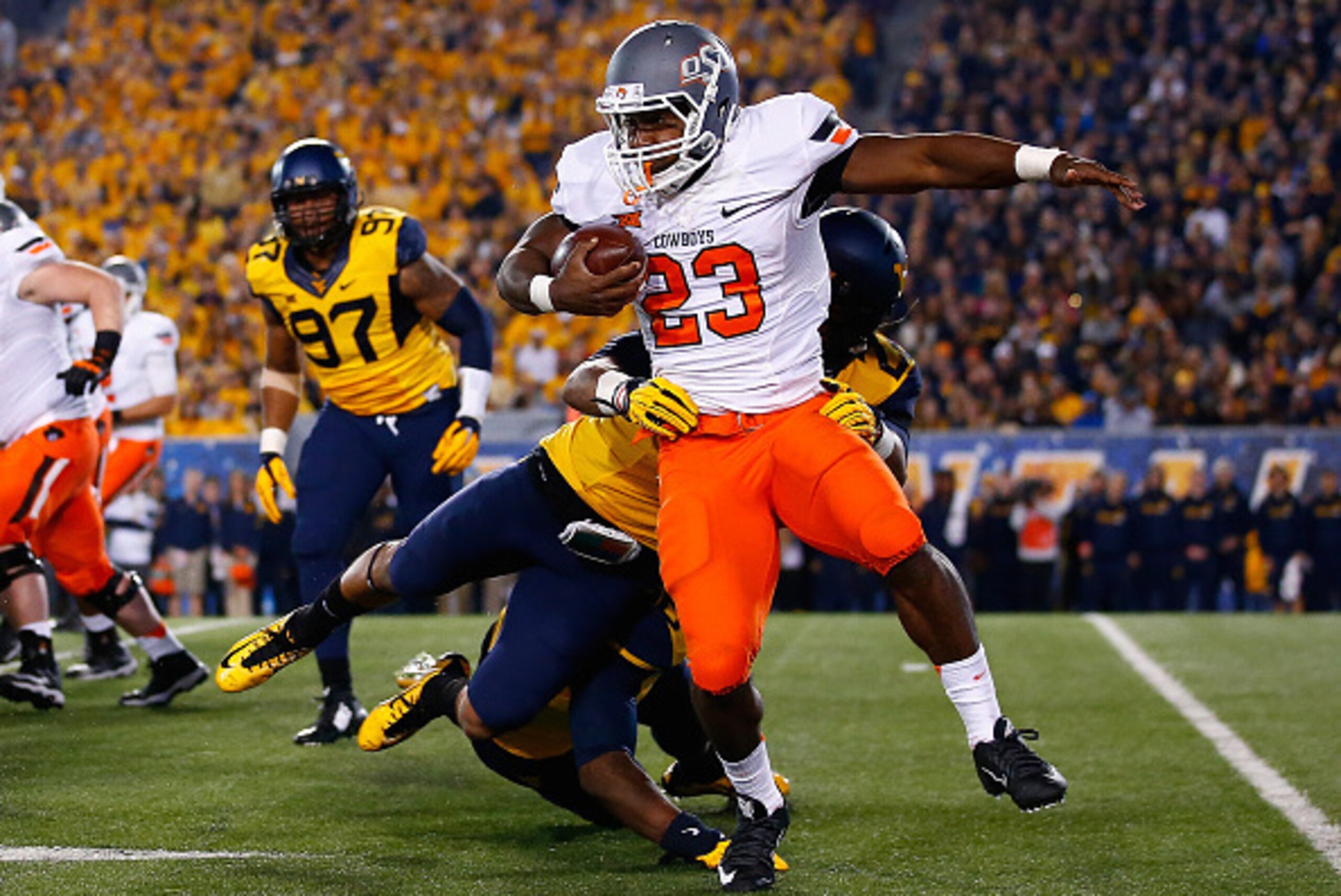 MORGANTOWN, WV - OCTOBER 10: Rennie Childs #23 of the Oklahoma State Cowboys runs with the ball against the West Virginia Mountaineers in the first half during the game at Mountaineer Field on October 10, 2015 in Morgantown, West Virginia.  (Photo by Jare