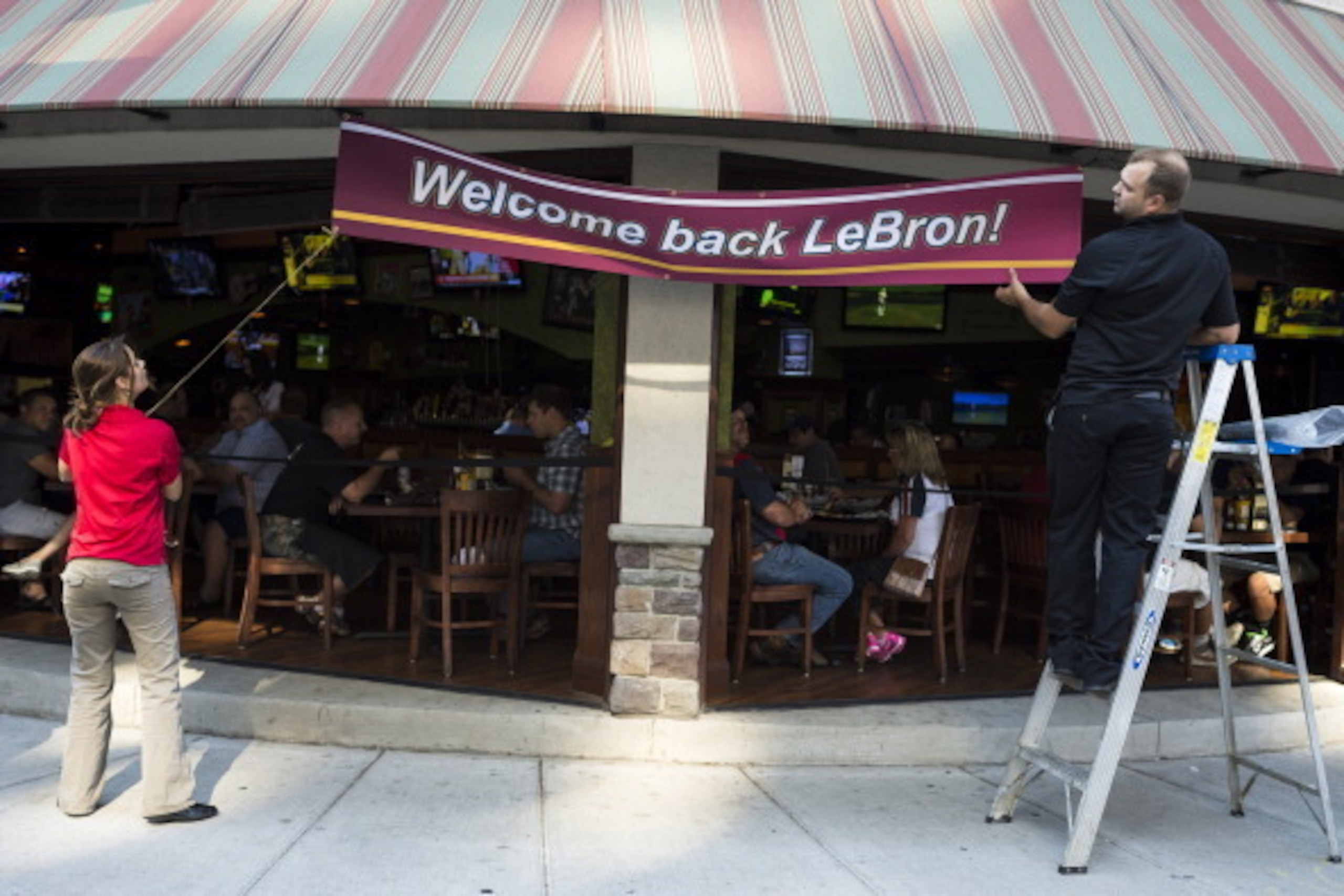 CLEVELAND, OH - JULY 11: Employees of The Tilted Kilt hang a banner to welcome back LeBron James on July 11, 2014 in Cleveland, Ohio. Earlier in the day James, born and raised in Akron, Ohio, announced his return to the Cleveland Cavaliers. (Photo by Ange CLEVELAND, OH - JULY 11: Employees of The Tilted Kilt hang a banner to welcome back LeBron James on July 11, 2014 in Cleveland, Ohio. Earlier in the day James, born and raised in Akron, Ohio, announced his return to the Cleveland Cavaliers. (Photo by Ange