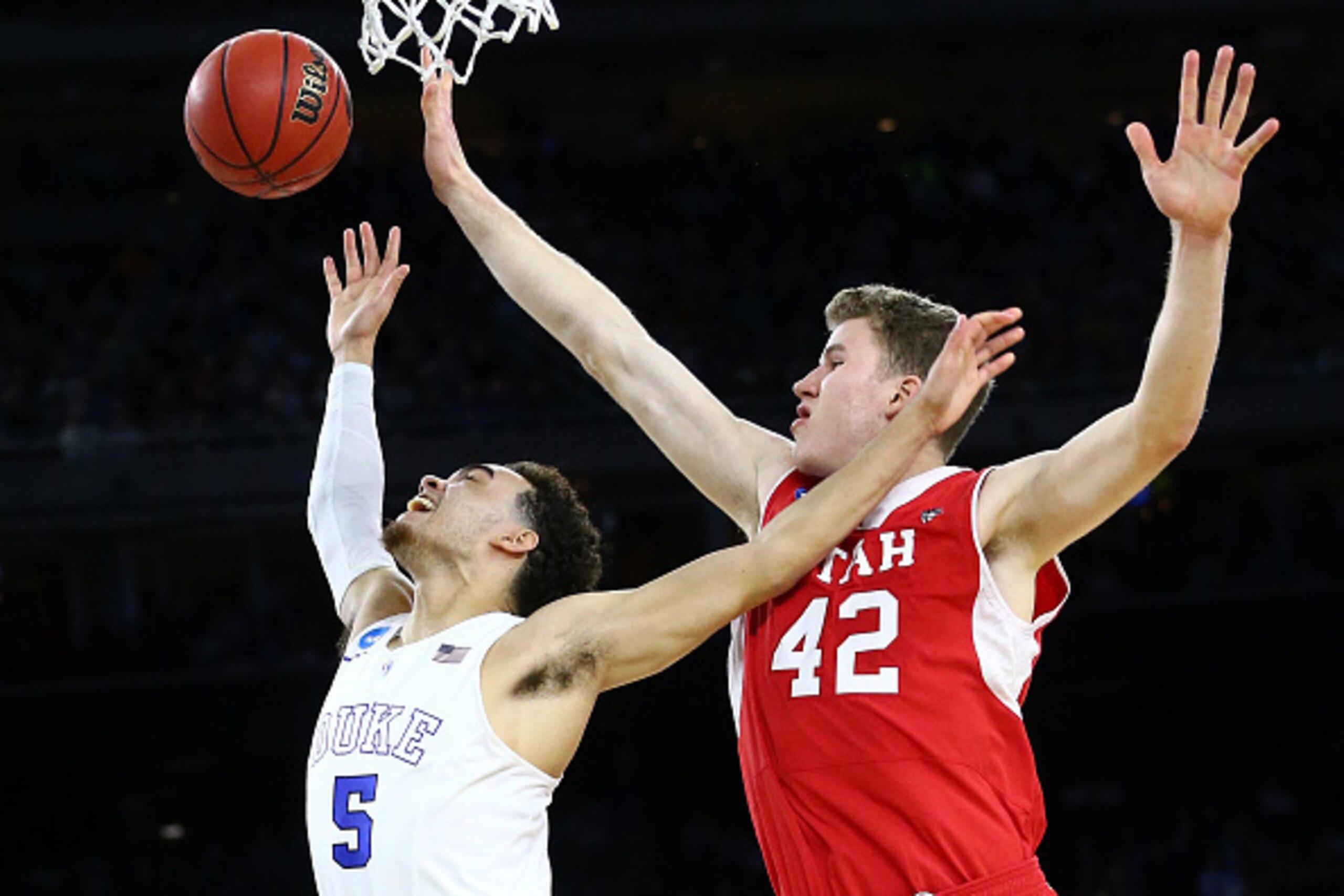 HOUSTON, TX - MARCH 27:  Tyus Jones #5 of the Duke Blue Devils goes for a layup as Jakob Poeltl #42 of the Utah Utes defends during a South Regional Semifinal game of the 2015 NCAA Men's Basketball Tournament at NRG Stadium on March 27, 2015 in Houston, T