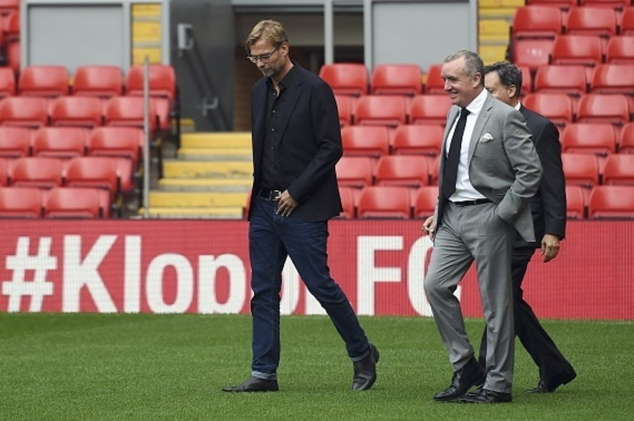 Liverpool's new German manager Jurgen Klopp (L) walks on the pitch with Liverpool's chairman Tom Werner (R obscured) and managing director Ian Ayre (C) after a press conference to announce his new appointment at Anfield in Liverpool, northwest England, on