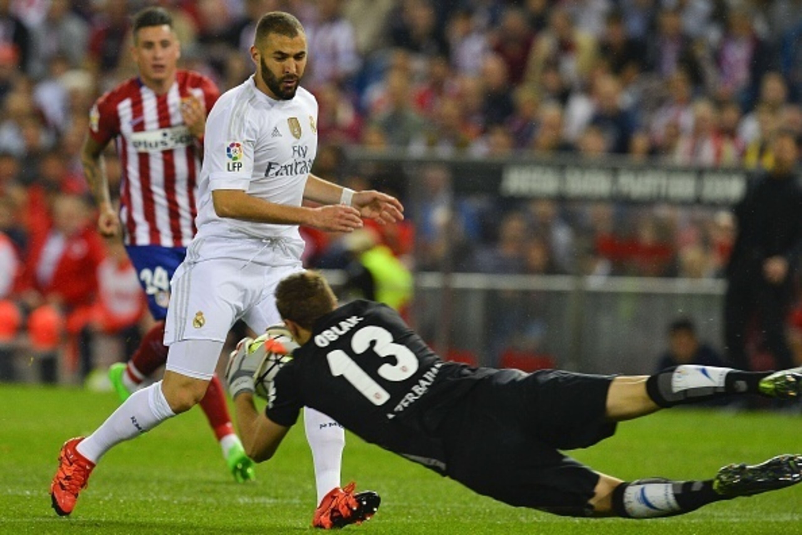Atletico Madrid's Slovenian goalkeeper Jan Oblak (R) grabs the ball past Real Madrid's French forward Karim Benzema during the Spanish league football match Club Atletico de Madrid vs Real Madrid CF at the Vicente Calderon stadium in Madrid on October 4, 