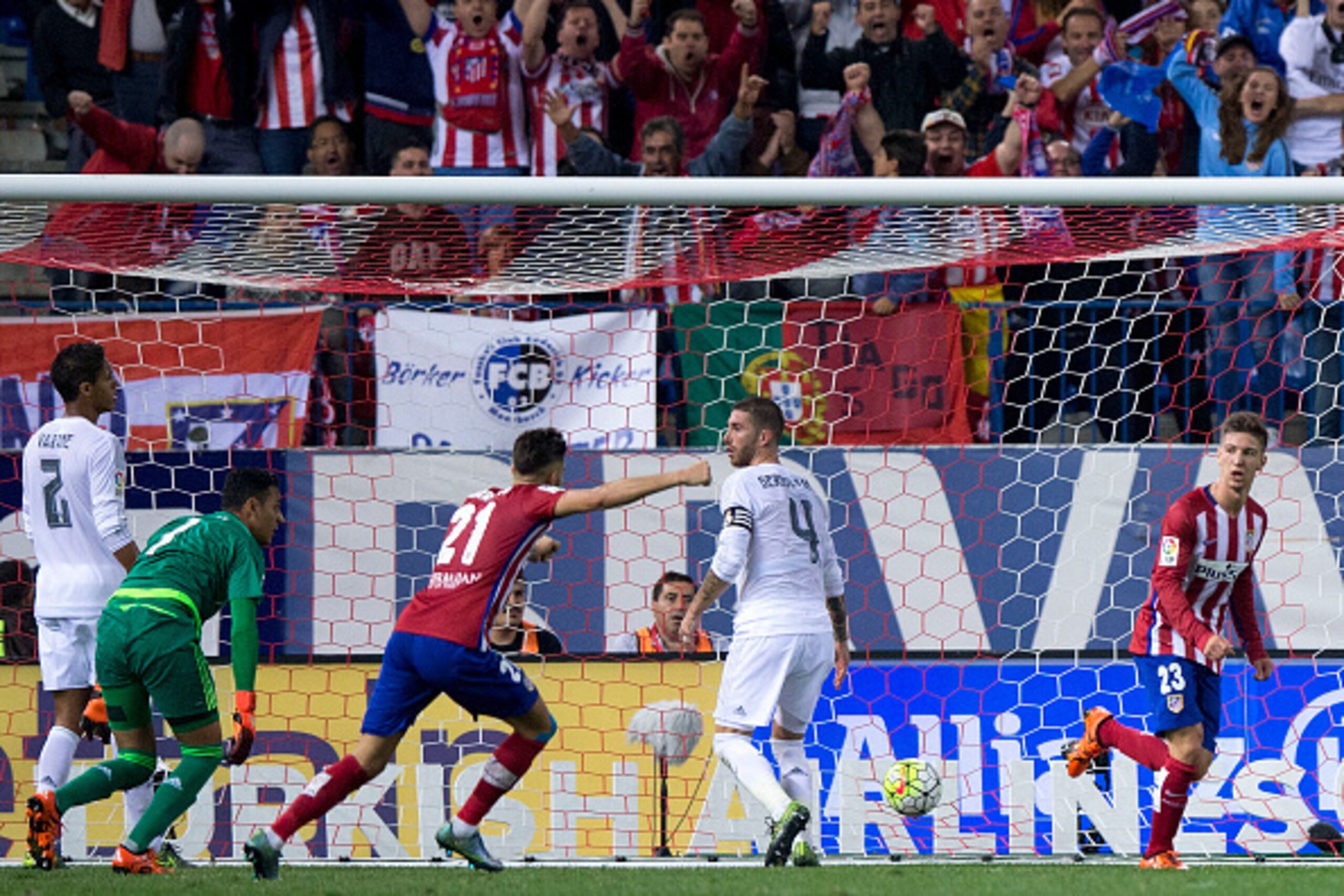 MADRID, SPAIN - OCTOBER 04:  Luciano Dario Vietto (R) of Atletico de Madrid celebrates scoring their opening goal with teammate Yannick Carrasco (3dL) as Sergio Ramos (2ndR) of Real Madrid CF reacts with teammates goalkeeper Keylor Navas (2ndL) and Raphae