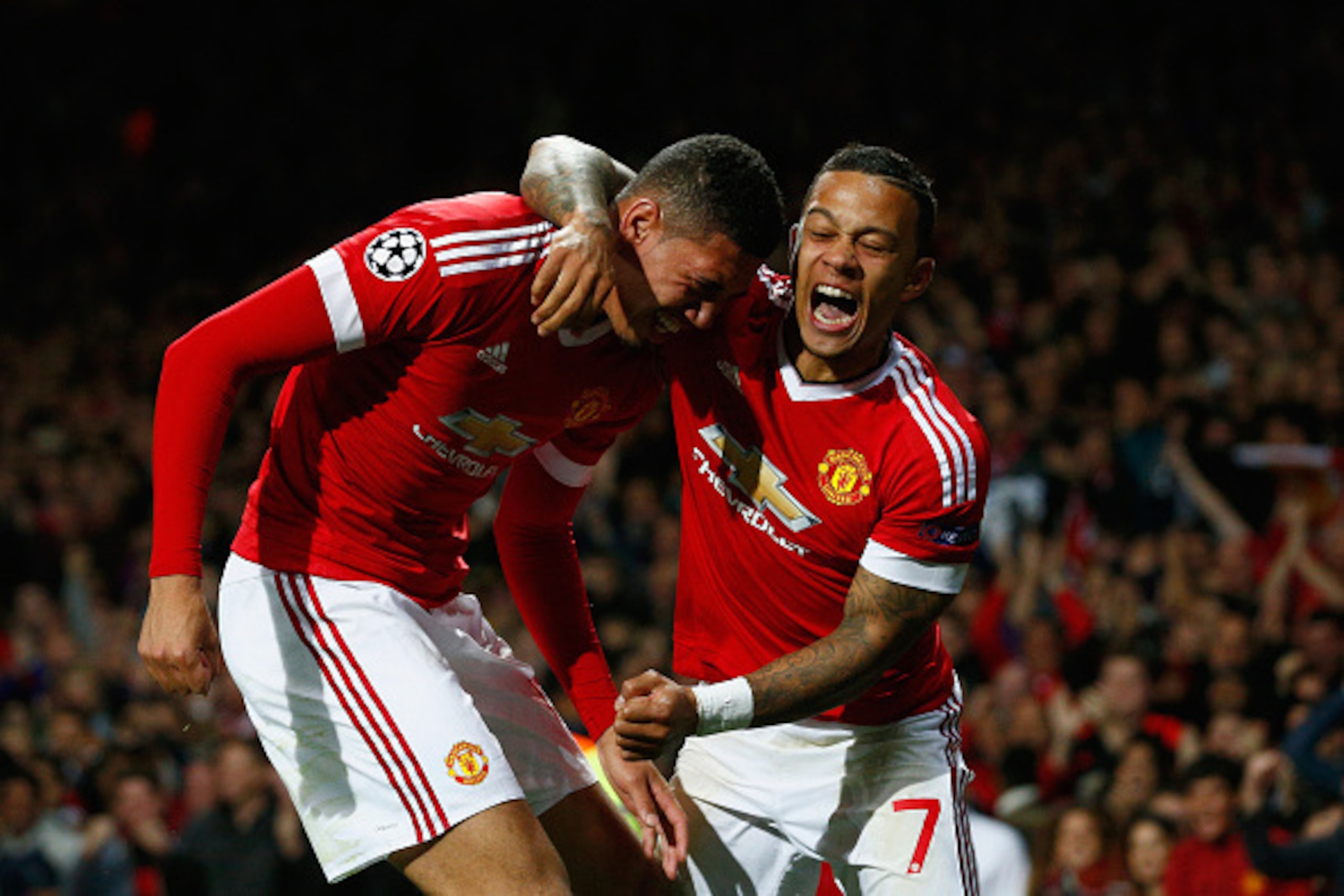 MANCHESTER, ENGLAND - SEPTEMBER 30:  Chris Smalling of Manchester United (L) celebrates with team mate Memphis Depay as he scores their second goal during the UEFA Champions League Group B match between Manchester United FC and VfL Wolfsburg at Old Traffo