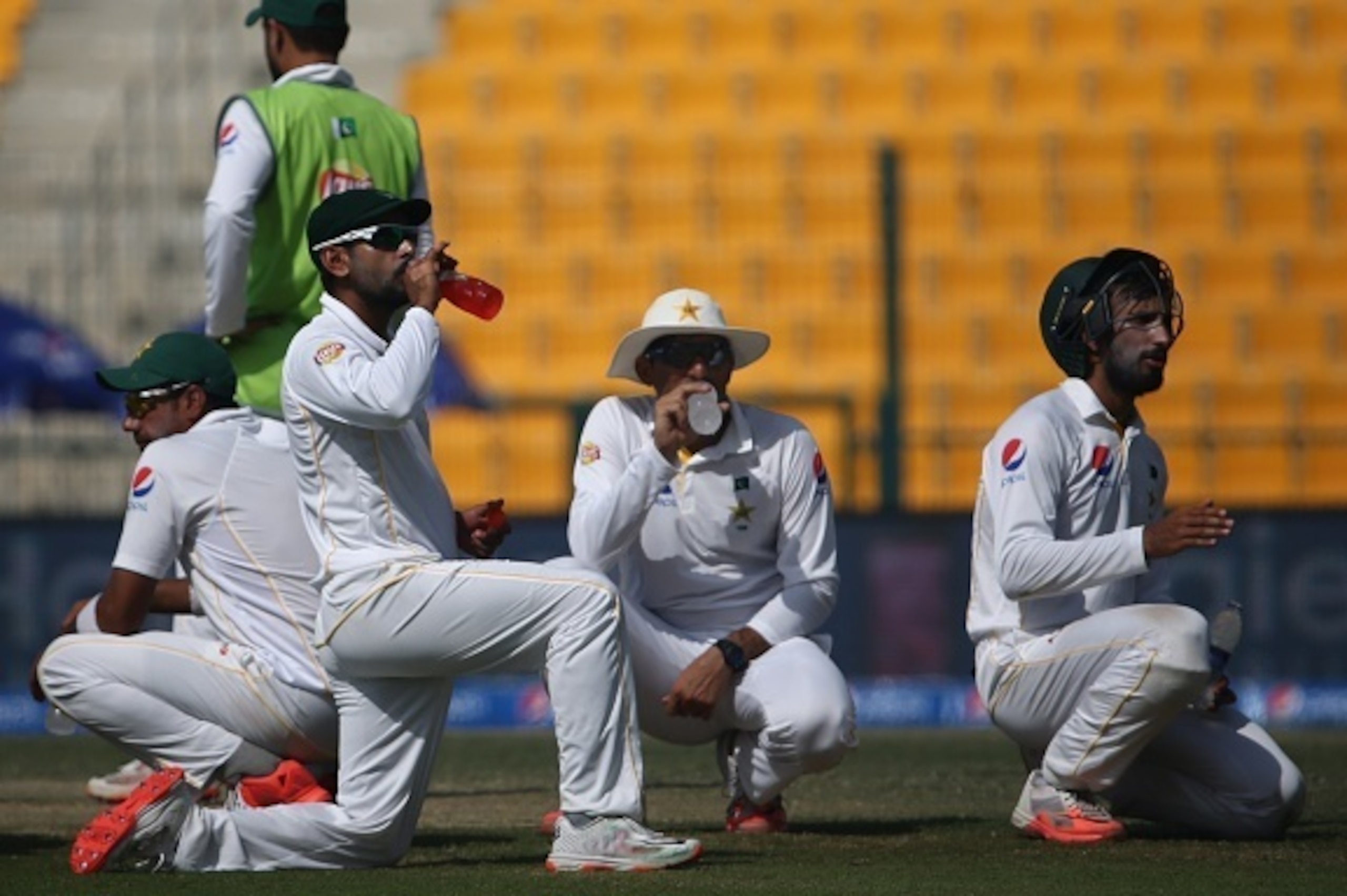 Pakistan players drink water during a short break in the third day's play of the first cricket Test match between Pakistan and England at The Sheikh Zayed International Cricket Stadium in Abu Dhabi on October 15, 2015. AFP PHOTO / MARWAN NAAMANI        (P