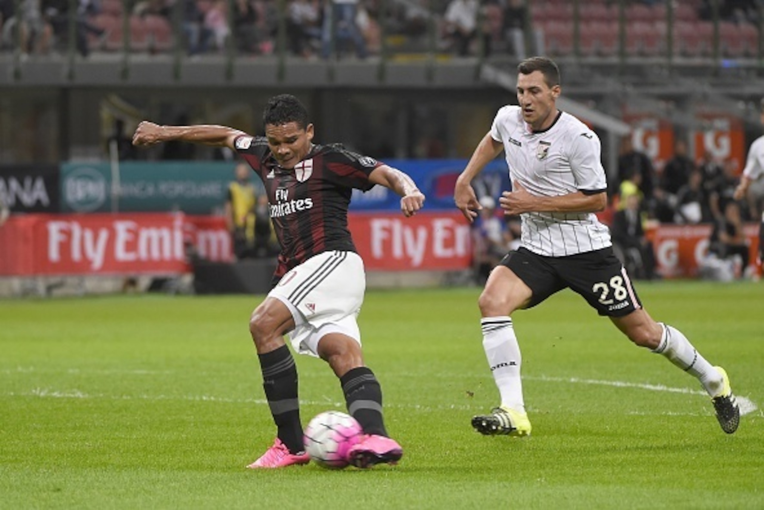AC Milan's forward from Colombia Carlos Bacca (L) takes a 'rabona ' trick shot in front of Palermo's midfielder from Croatia Mato Jajalo during the Italian Serie A football match AC Milan vs Palermo on September 19, 2015 at the San Siro Stadium stadium in