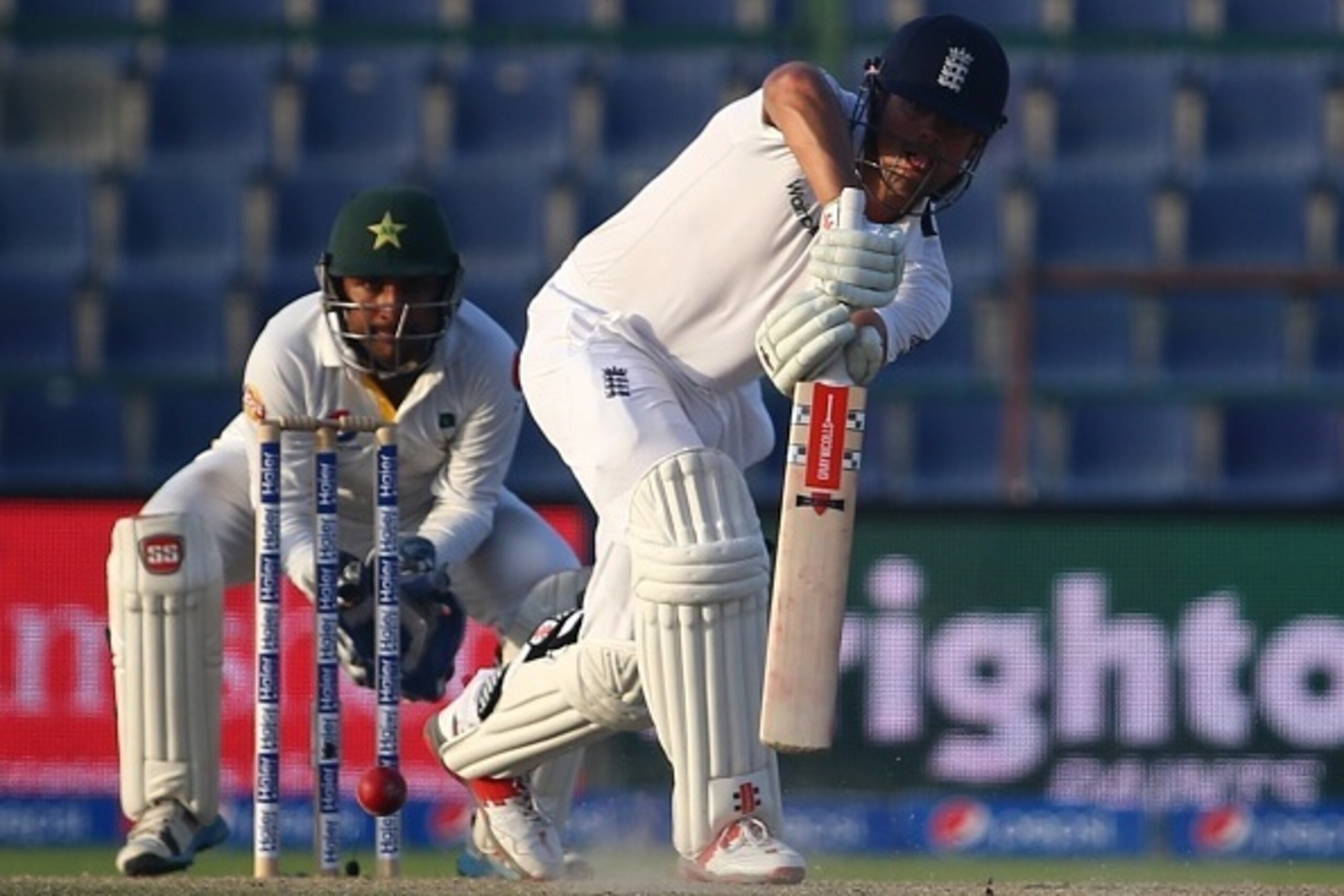 England's Alastair Cook (R) is watched by Pakistan's wicketkeeper Sarfraz Ahmed as he plays a shot during the fourth day's play of the first cricket Test match between Pakistan and England at The Sheikh Zayed International Cricket Stadium in Abu Dhabi on 