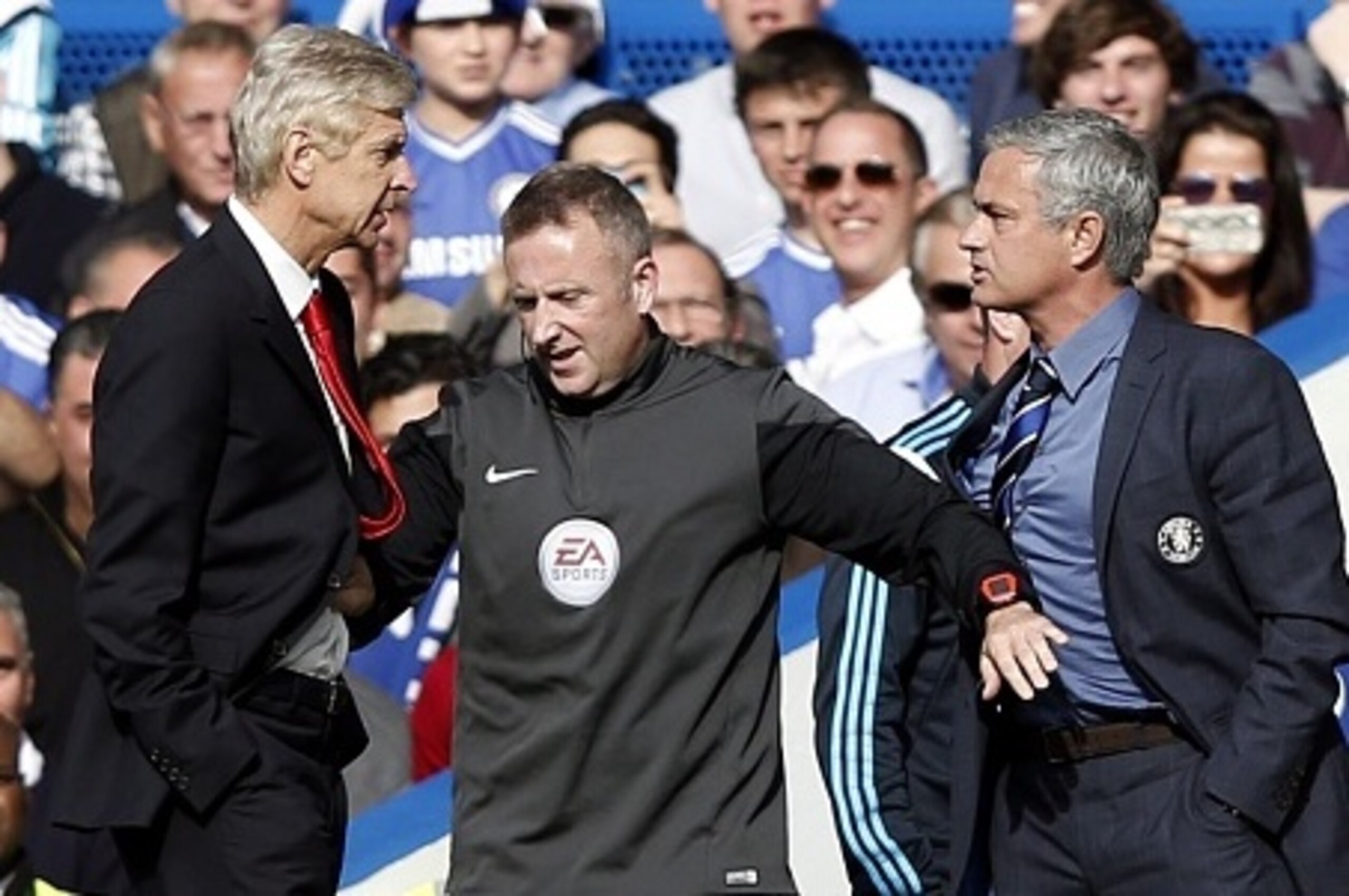 Chelsea's Portuguese manager Jose Mourinho (R) and Arsenal's French manager Arsene Wenger (L) are kept apart by the fourth official Jonathan Moss during the English Premier League football match between Chelsea and Arsenal at Stamford Bridge in London on 
