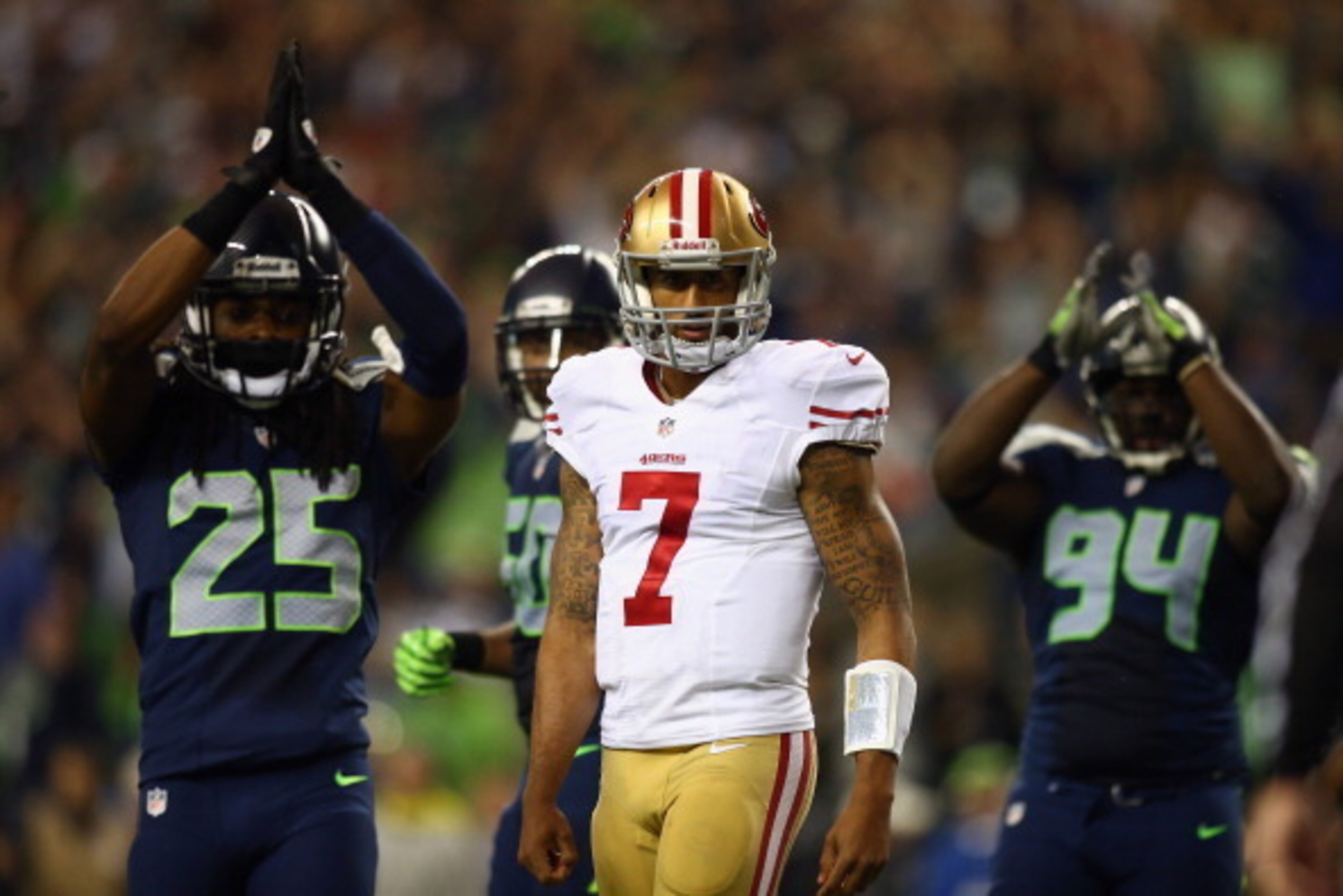 SEATTLE, WA - SEPTEMBER 15:  Colin Kaepernick #7 of the San Francisco 49ers looks on as Richard Sherman #25 and D'Anthony Smith #94 of the Seattle Seahawks celebrate a saftey during their game at Qwest Field on September 15, 2013 in Seattle, Washington.  