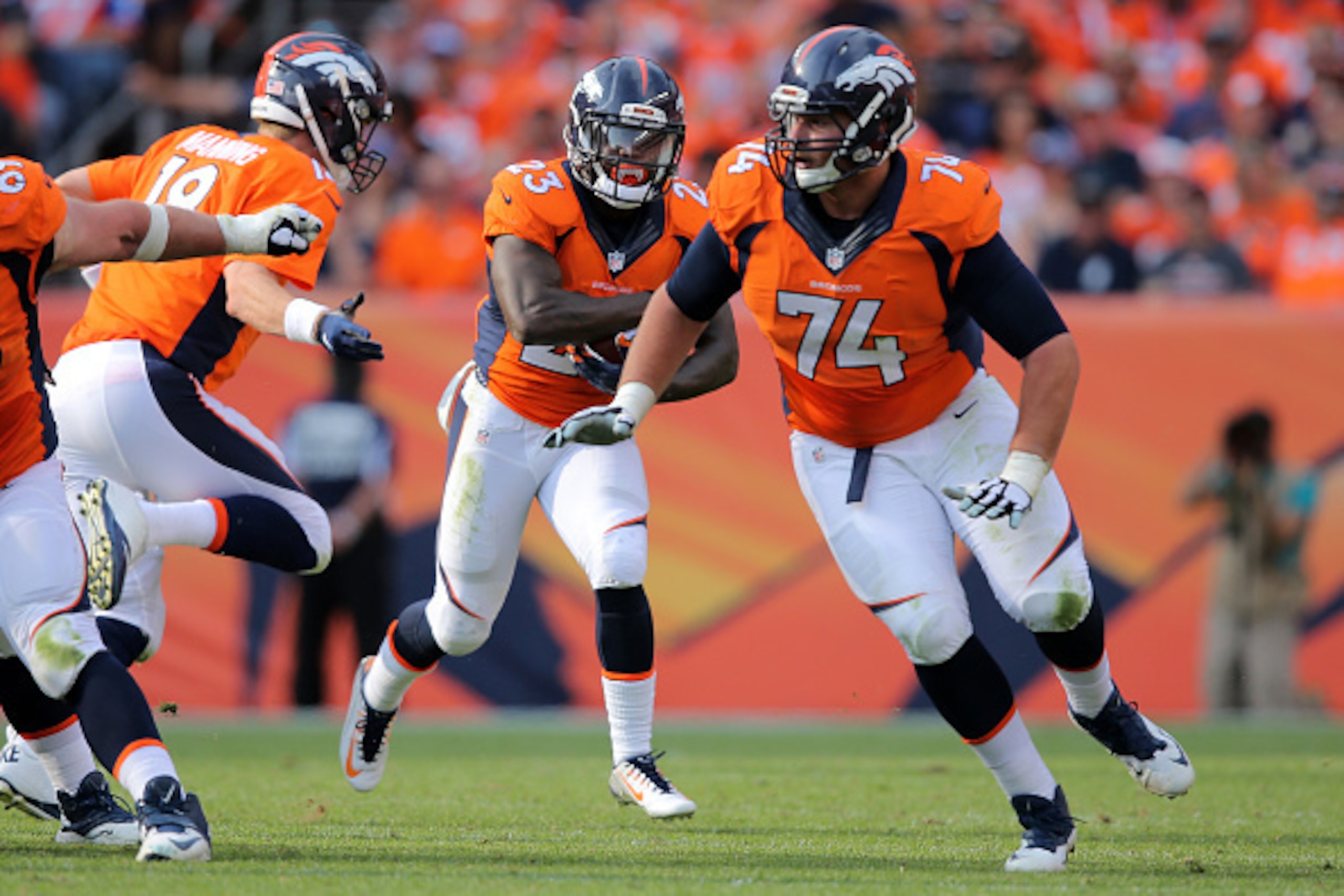 DENVER, CO - SEPTEMBER 13:  Ronnie Hillman #23 of the Denver Broncos takes a handoff from Peyton Manning #18 of the Denver Broncos and follows the block of Ty Sambrailo #74 of the Denver Broncos against the Baltimore Ravens at Sports Authority Field at Mi