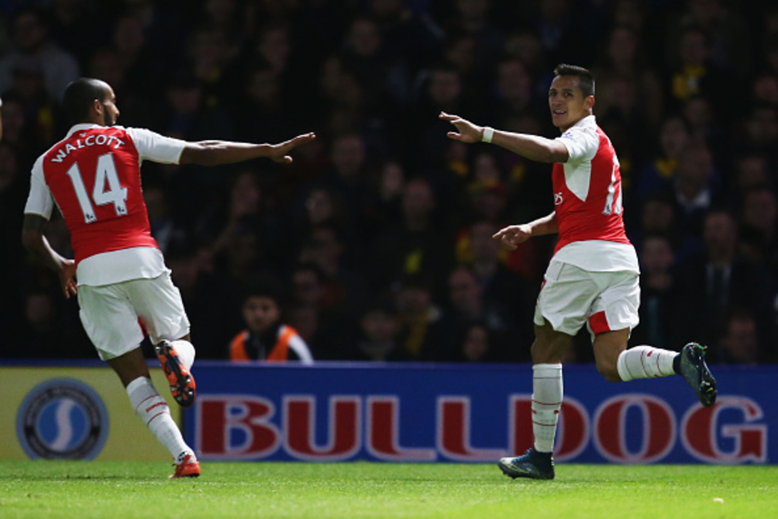 WATFORD, ENGLAND - OCTOBER 17:  Alexis Sanchez of Arsenal (R) celebrates with team mate Theo Walcott as he scores their first goal during the Barclays Premier League match between Watford and Arsenal at Vicarage Road on October 17, 2015 in Watford, Englan