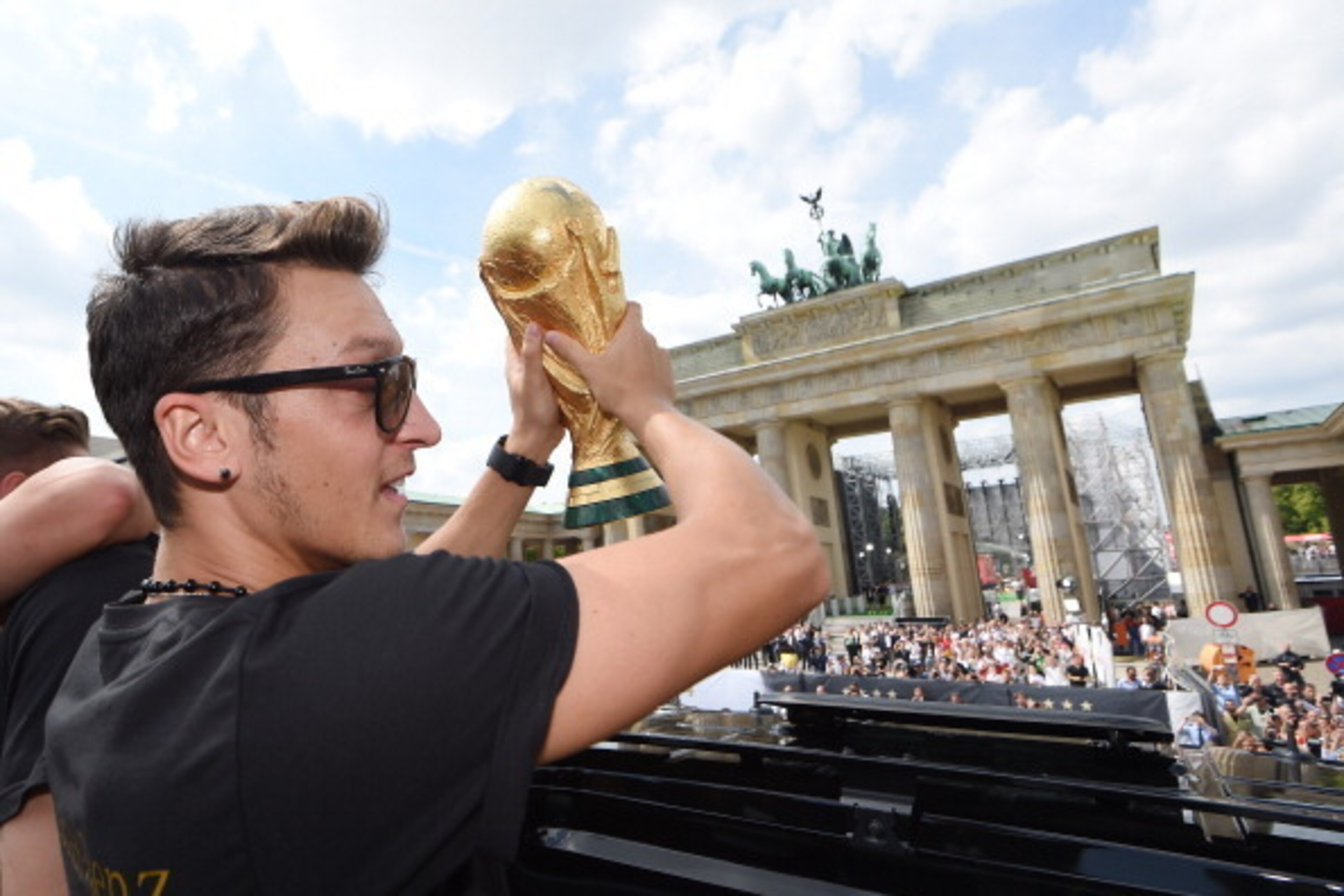 BERLIN, GERMANY - JULY 15: Mesut Oezil celebrates on the open top bus at the German team victory ceremony on July 15, 2014 in Berlin, Germany. Germany won the 2014 FIFA World Cup Brazil match against Argentina in Rio de Janeiro on July 13.  (Photo by Mark