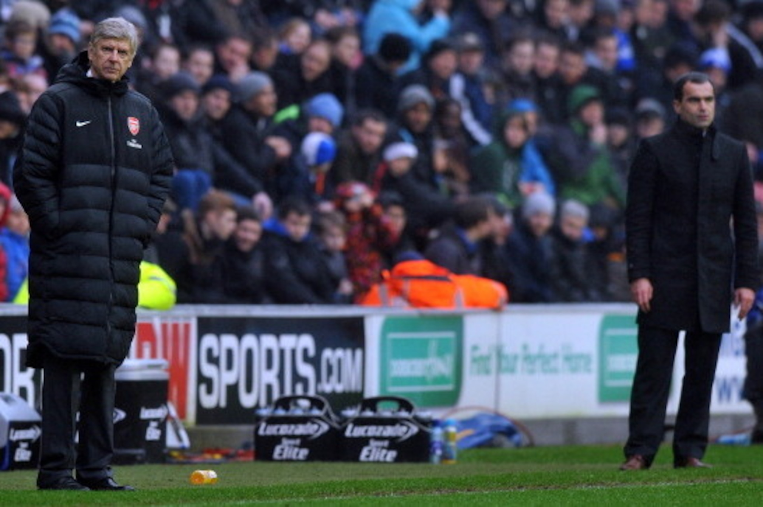 Arsenal's French manager Arsene Wenger (L) and Wigan Athletic's Spanish manager Roberto Martinez watch play during the English Premier League football match between Wigan Athletic and Arsenal at The DW Stadium in Wigan, north-west England on December 22, 