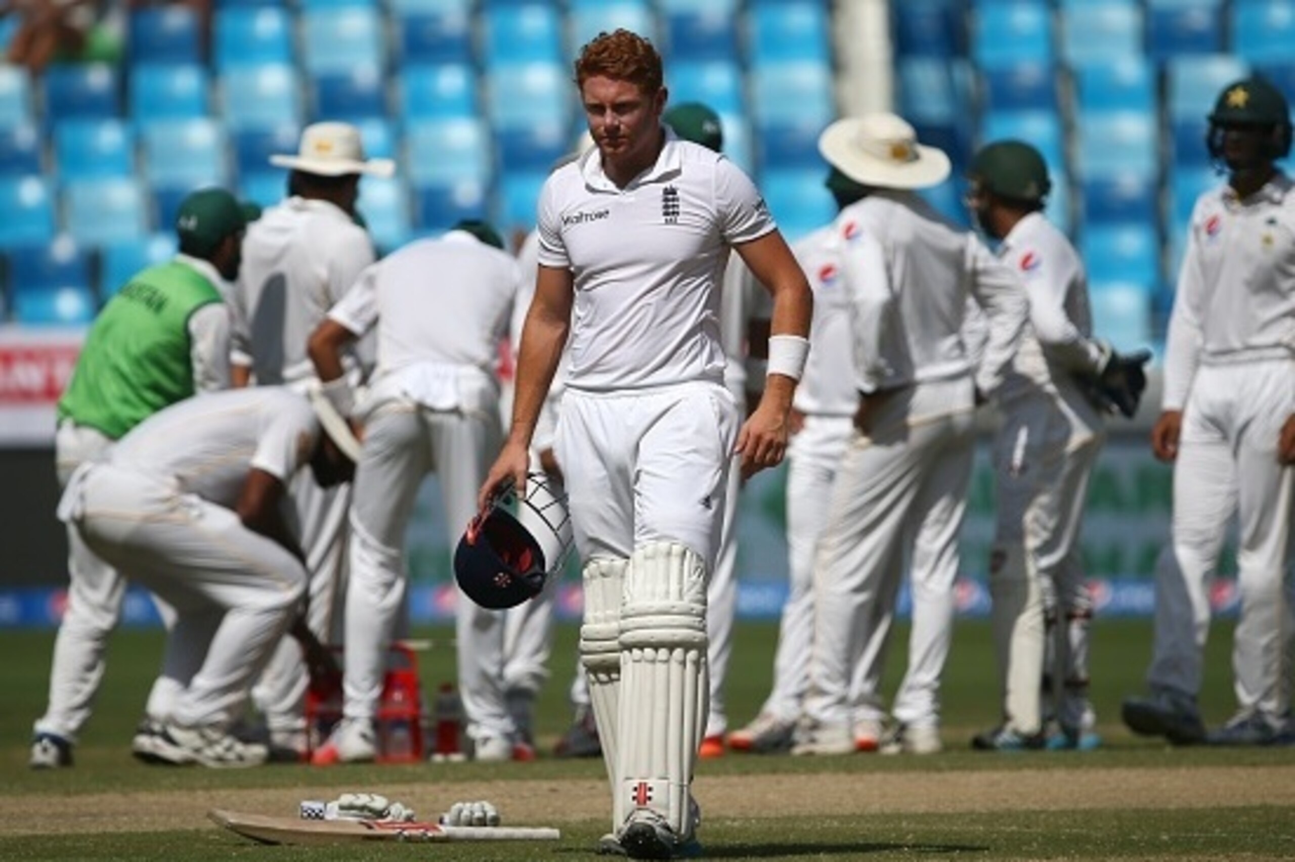 England's Jonny Bairstow (C) looks on as Pakistan's players (background) celebrate the dismissal of England's Adil Rashid for a duck during the third day of the second Test match between Pakistan and England in Dubai on October 24, 2015. AFP PHOTO / MARWA