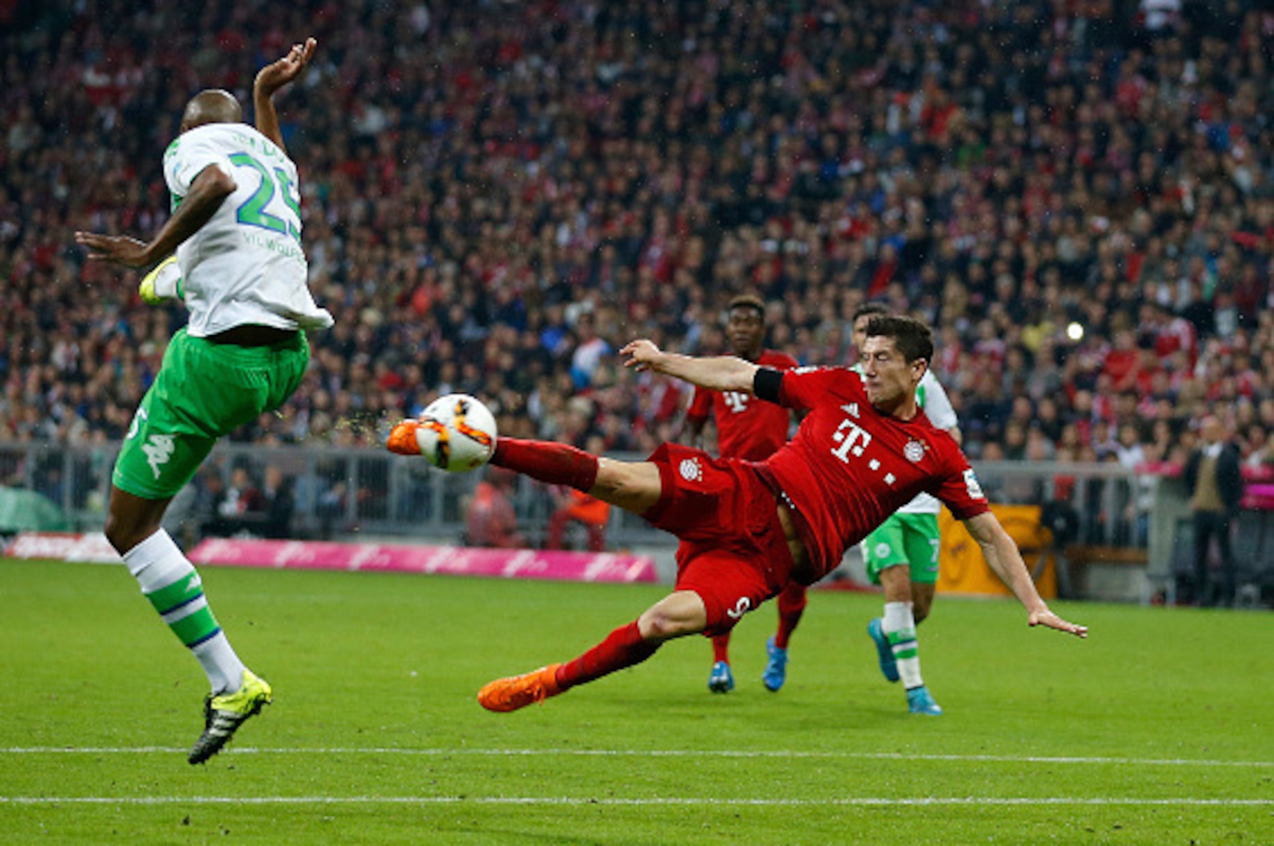 MUNICH, BAYERN - SEPTEMBER 22:  Robert Lewandowski (R) of Bayern Munich scores his 5th goal with a sideways scissor-kick during the Bundesliga match between FC Bayern Muenchen and VfL Wolfsburg at Allianz Arena on September 22, 2015 in Munich, Germany.  (