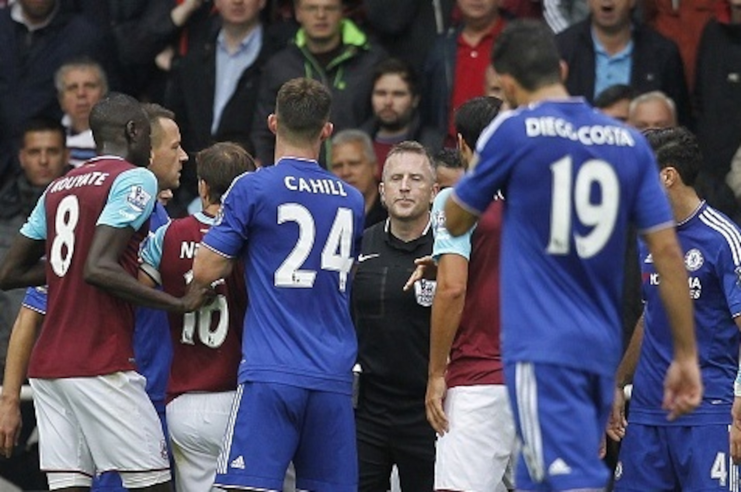 Chelsea and West Ham players surround referee Jonathan Moss (C) as he prepares to make a decision following a challenge by Chelsea's Serbian midfielder Nemanja Matic on West Ham United's Senegalese striker Diafra Sakho during the English Premier League fo
