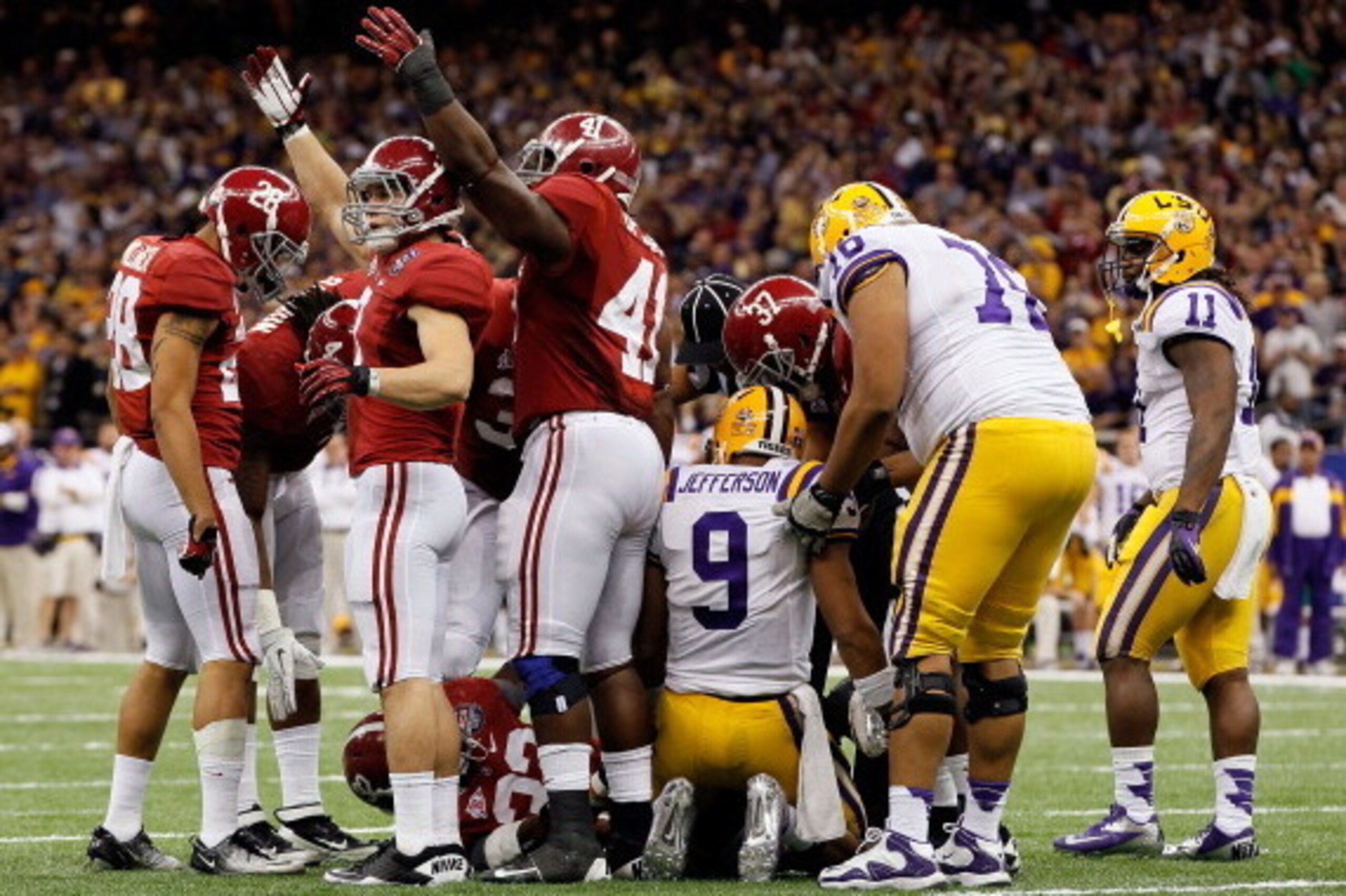 NEW ORLEANS, LA - JANUARY 09:  Vinnie Sunseri #3 and Courtney Upshaw #41 of the Alabama Crimson Tide gestures for help after the injury of teammate C.J. Mosley #32 as Jordan Jefferson #9 and Chris Faulk #76 of the Louisiana State University Tigers look on