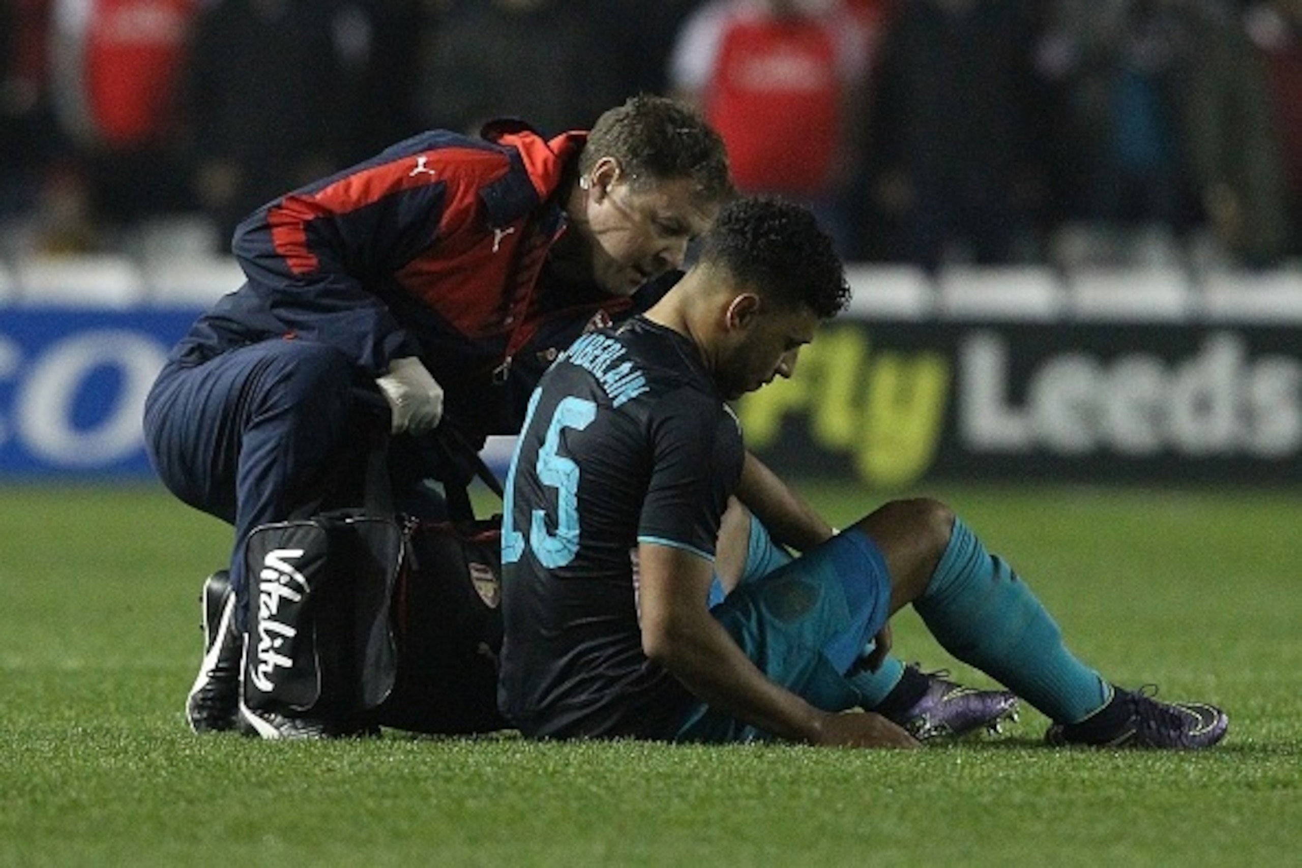 Arsenal's English striker Oxlade-Chamberlain (R) sits on the pitch injured before being substituted-off following a heavy tackle during the English League Cup fourth round football match between Sheffield Wednesday and Arsenal at The Hillsborough Stadium 