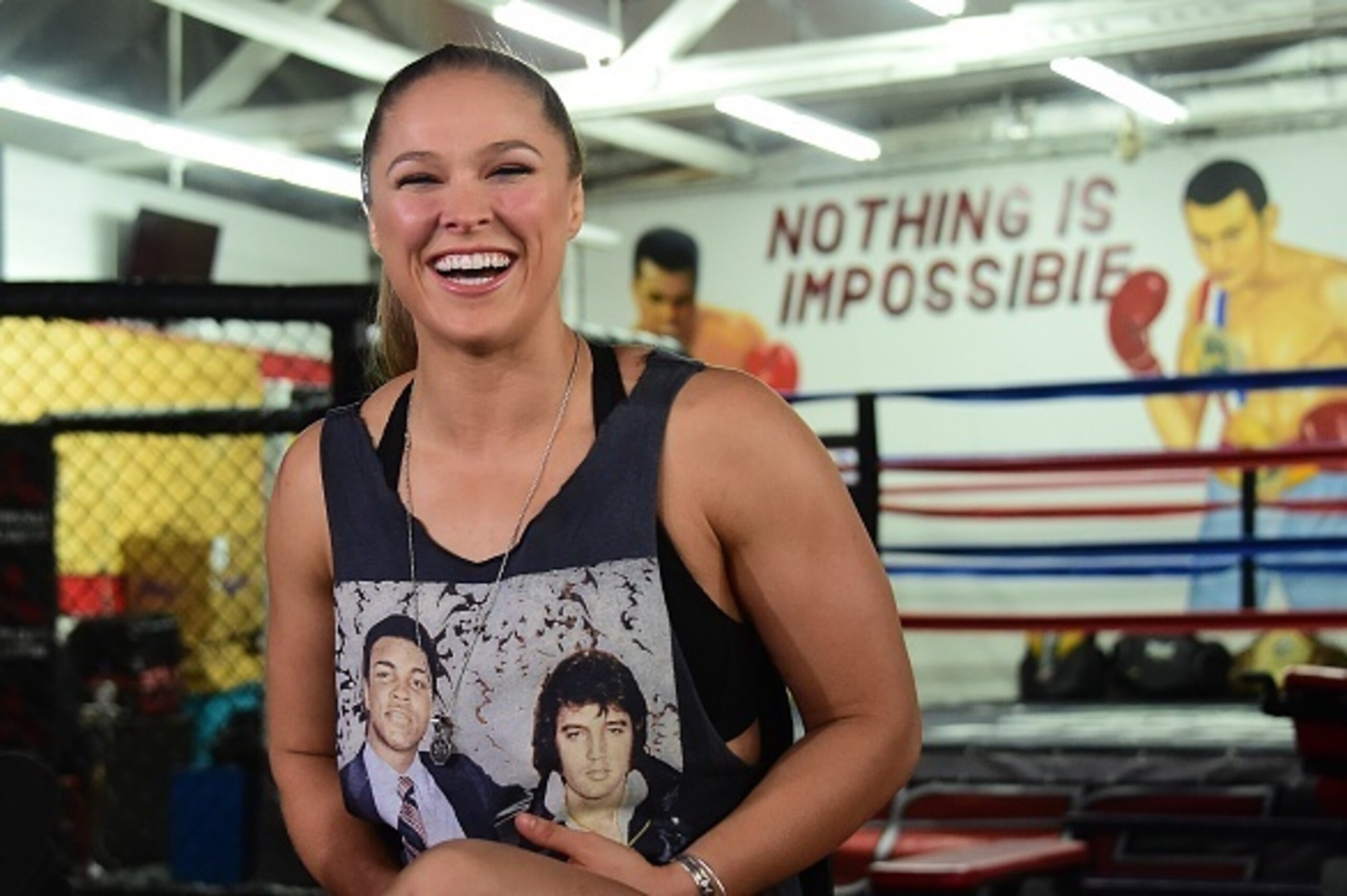 Mixed Martial Arts (MMA) fighter Ronda Rousey, wearing a shirt with portraits of former heavyweight  boxing champion Muhammad Ali (L) and the late US singer Elvis Presley (R),  responds to questions during media day in Glendale, California on October 27, 