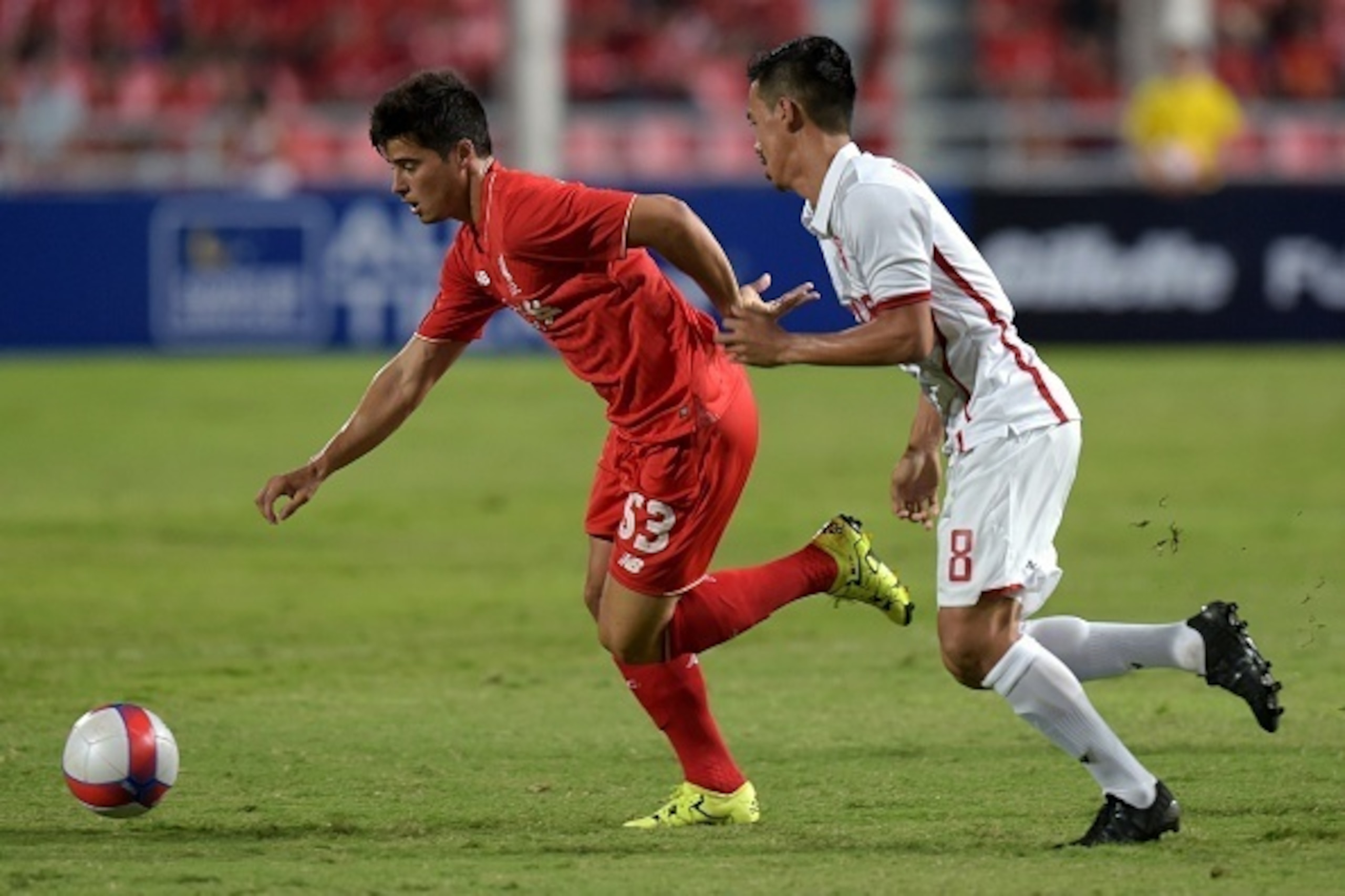 Liverpool football player Joao Carlos Teixeira (L) battles for the ball with Witthaya Madlam (R) of Thailand All Stars at Rajamangala stadium in Bangkok on July 14, 2015.  AFP PHOTO / PORNCHAI KITTIWONGSAKUL        (Photo credit should read PORNCHAI KITTI