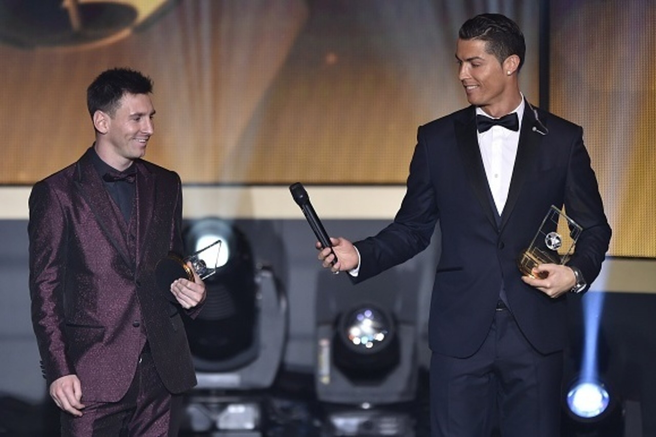 Real Madrid and Portugal forward Cristiano Ronaldo hands a microhpone to Barcelona and Argentina forward Lionel Messi (L) as they stand on stage after being selected in the 2014 FIFA FIFPro World XI during the FIFA Ballon d'Or award ceremony at the Kongre