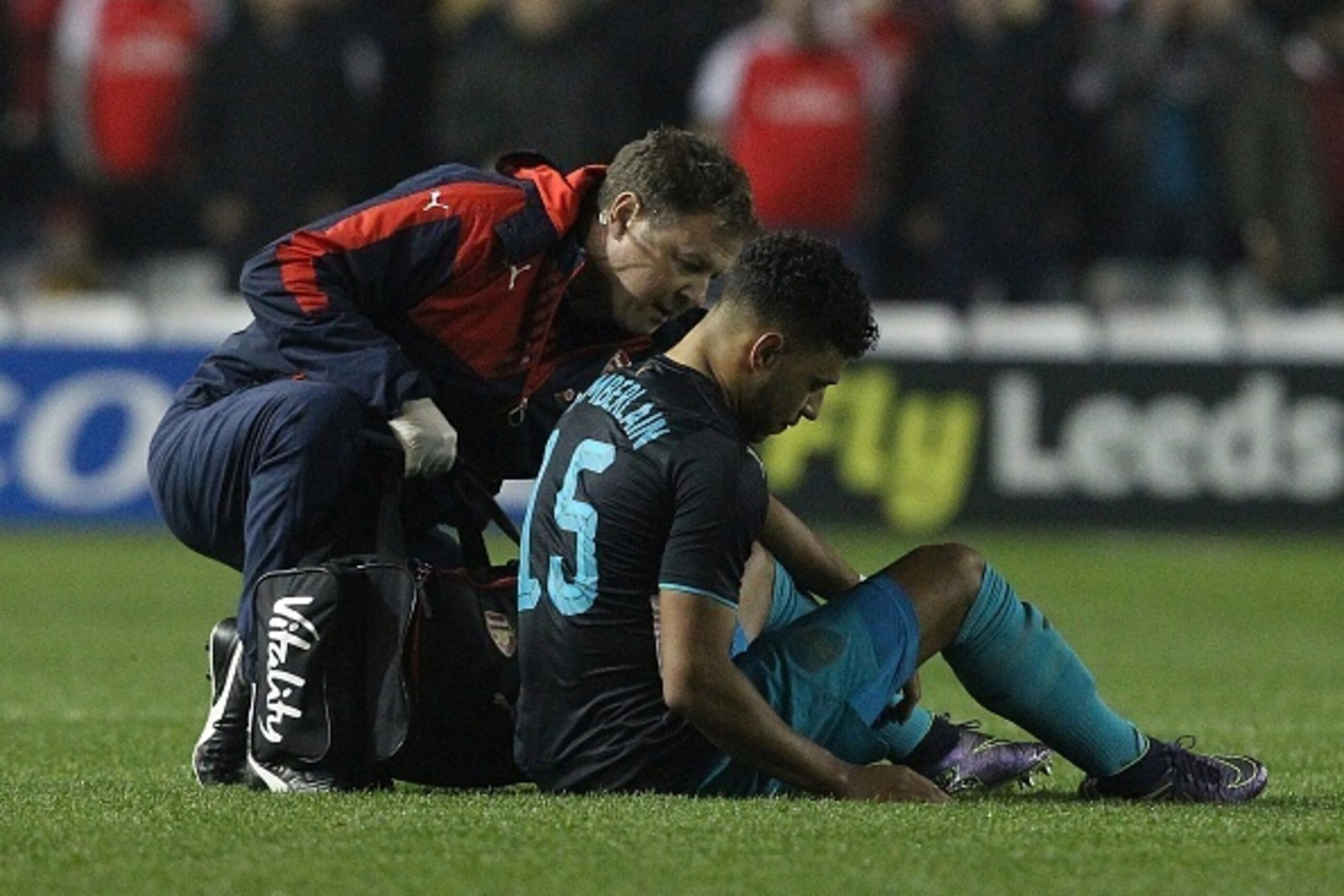 Arsenal's English striker Oxlade-Chamberlain (R) sits on the pitch injured before being substituted-off following a heavy tackle during the English League Cup fourth round football match between Sheffield Wednesday and Arsenal at The Hillsborough Stadium 