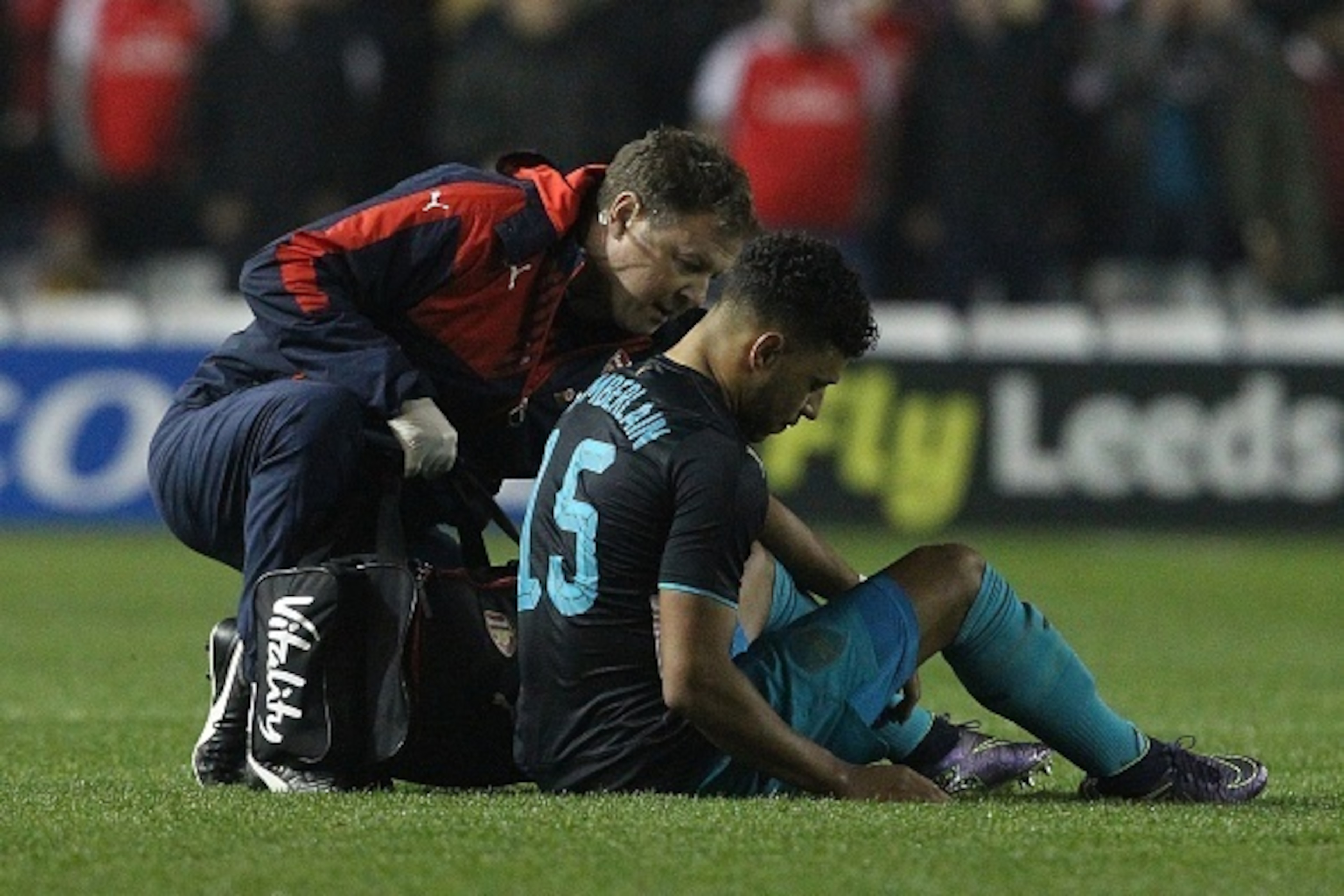 Arsenal's English striker Oxlade-Chamberlain (R) sits on the pitch injured before being substituted-off following a heavy tackle during the English League Cup fourth round football match between Sheffield Wednesday and Arsenal at The Hillsborough Stadium 