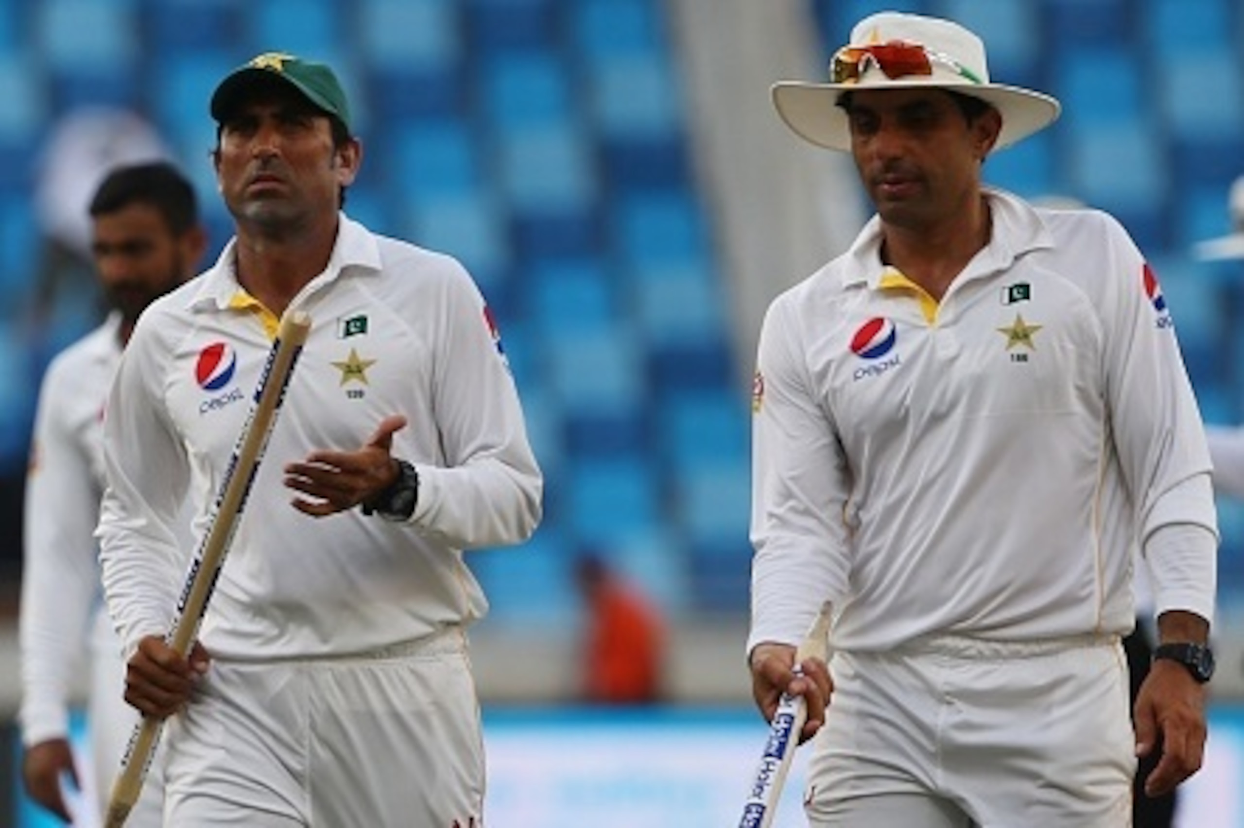 Pakistan's Younis Khan (L) and Misbah Ul Haq leave the green with the stumps after winning the second Test cricket match between Pakistan and England in the Gulf Emirate of Dubai on October 26, 2015. AFP PHOTO / MARWAN NAAMANI        (Photo credit should 