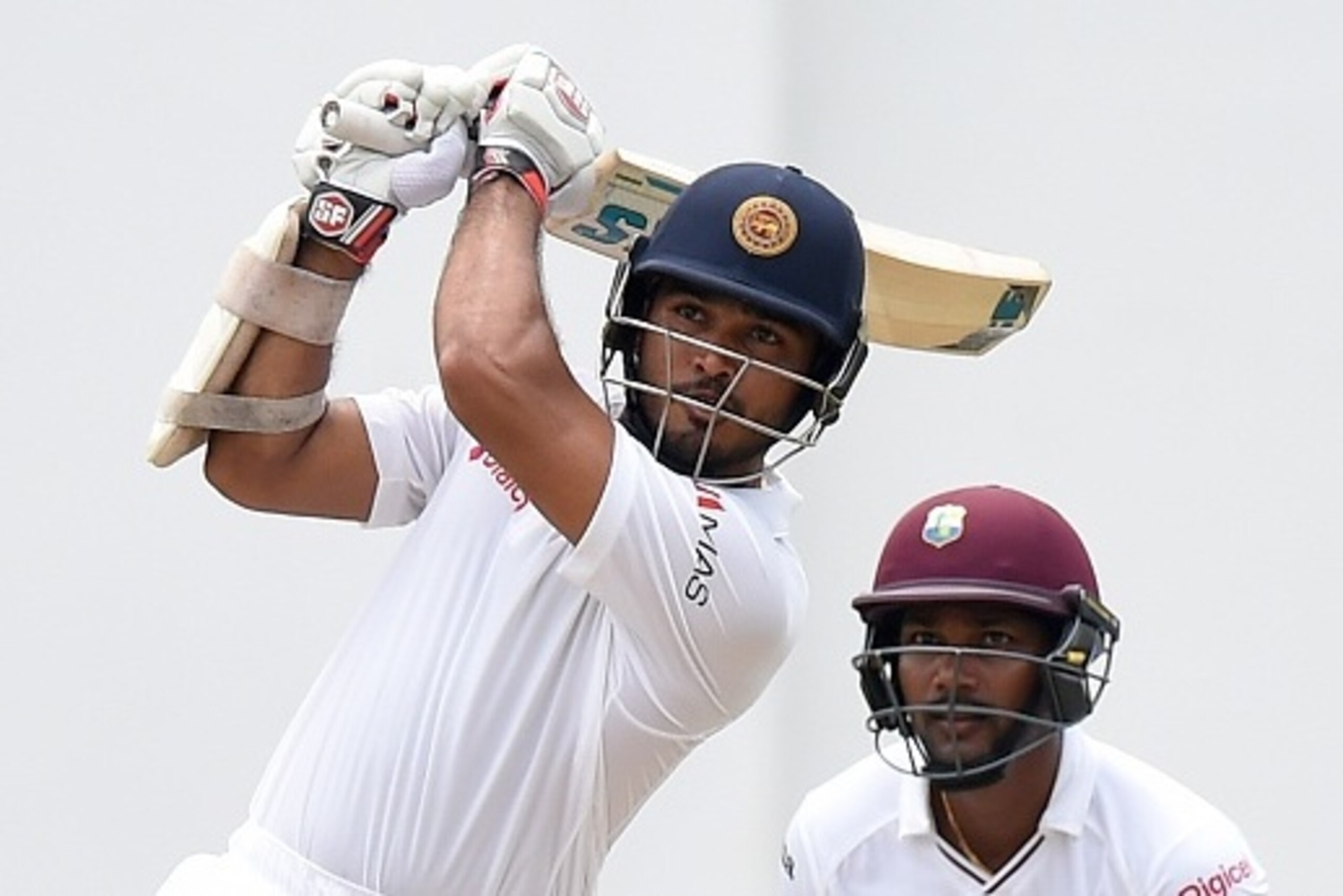 Sri Lankan cricketer Milinda Siriwardana (L) plays a shot as West Indies wicketkeeper Denesh Ramdin looks on during the third day of the second Test match between Sri Lanka and the West Indies at the P. Sara Oval Cricket Stadium in Colombo on October 24,