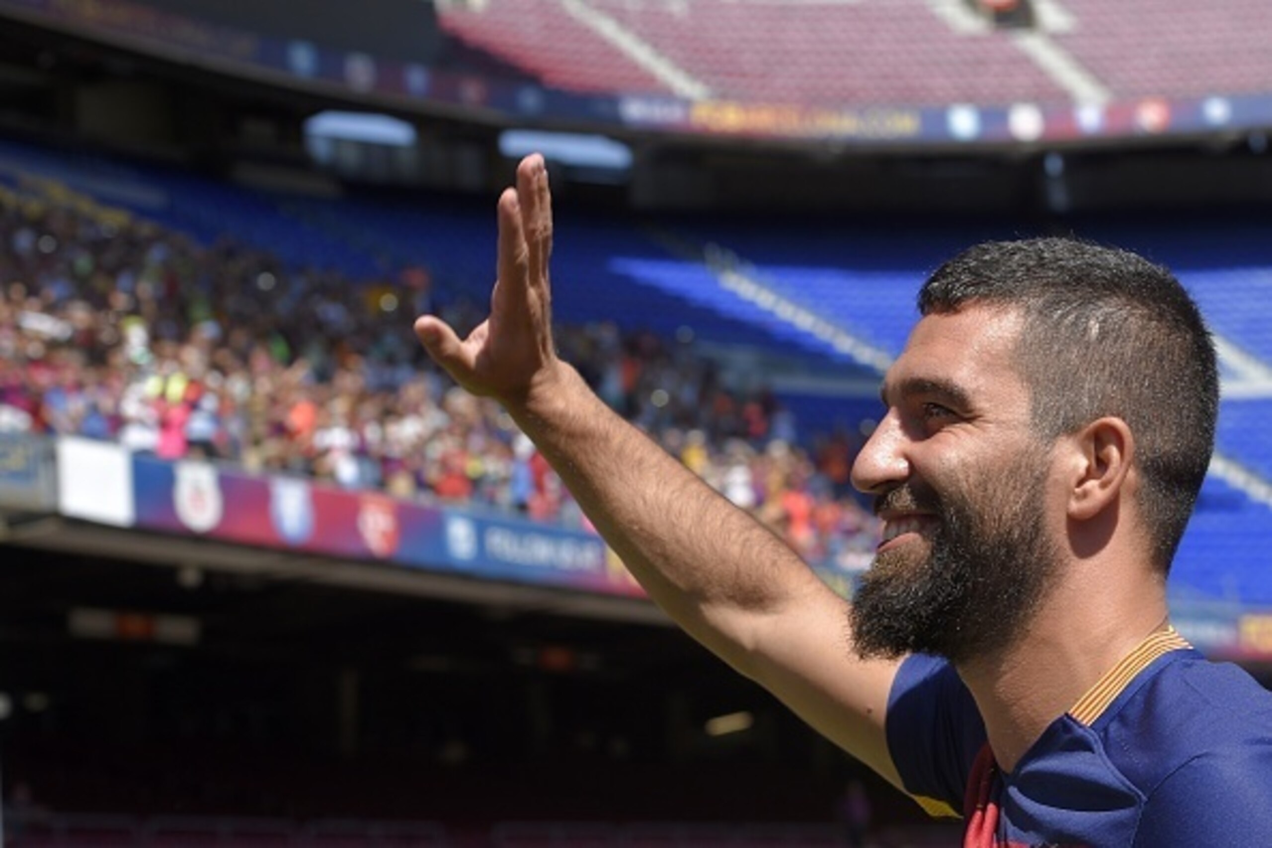 Barcelona's new player Turkish Arda Turan waves during his official presentation at the Camp Nou stadium in Barcelona, after signing his new contract with the Catalan club, on July 10, 2015. Barcelona will keep more than 60 million euros ($65 million) of 