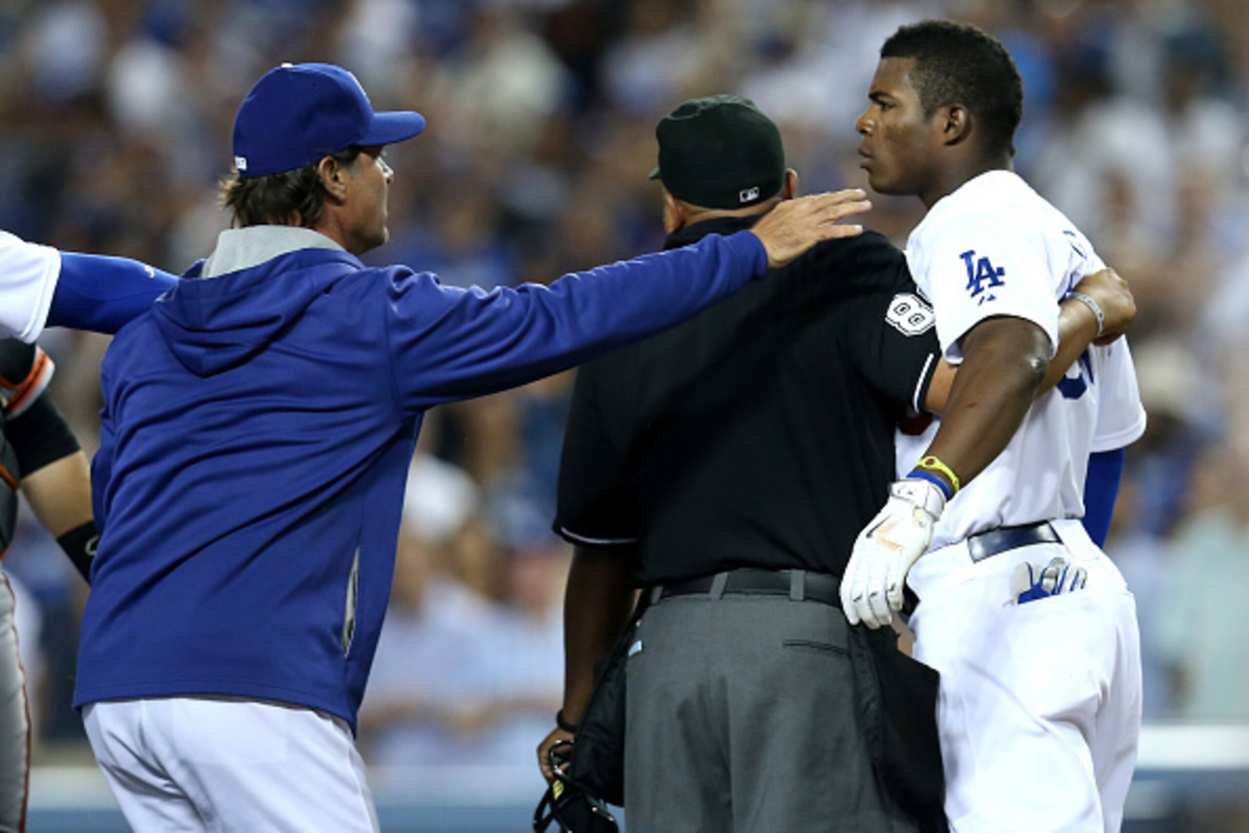 LOS ANGELES, CA - SEPTEMBER 23:  Yasiel Puig #66 of the Los Angeles Dodgers is restrained by manager Don Mattingly and home plate umpire Adrian Johnson after Puig was hit by a pitch from Madison Bumgarner of the San Francisco Giants at Dodger Stadium on S