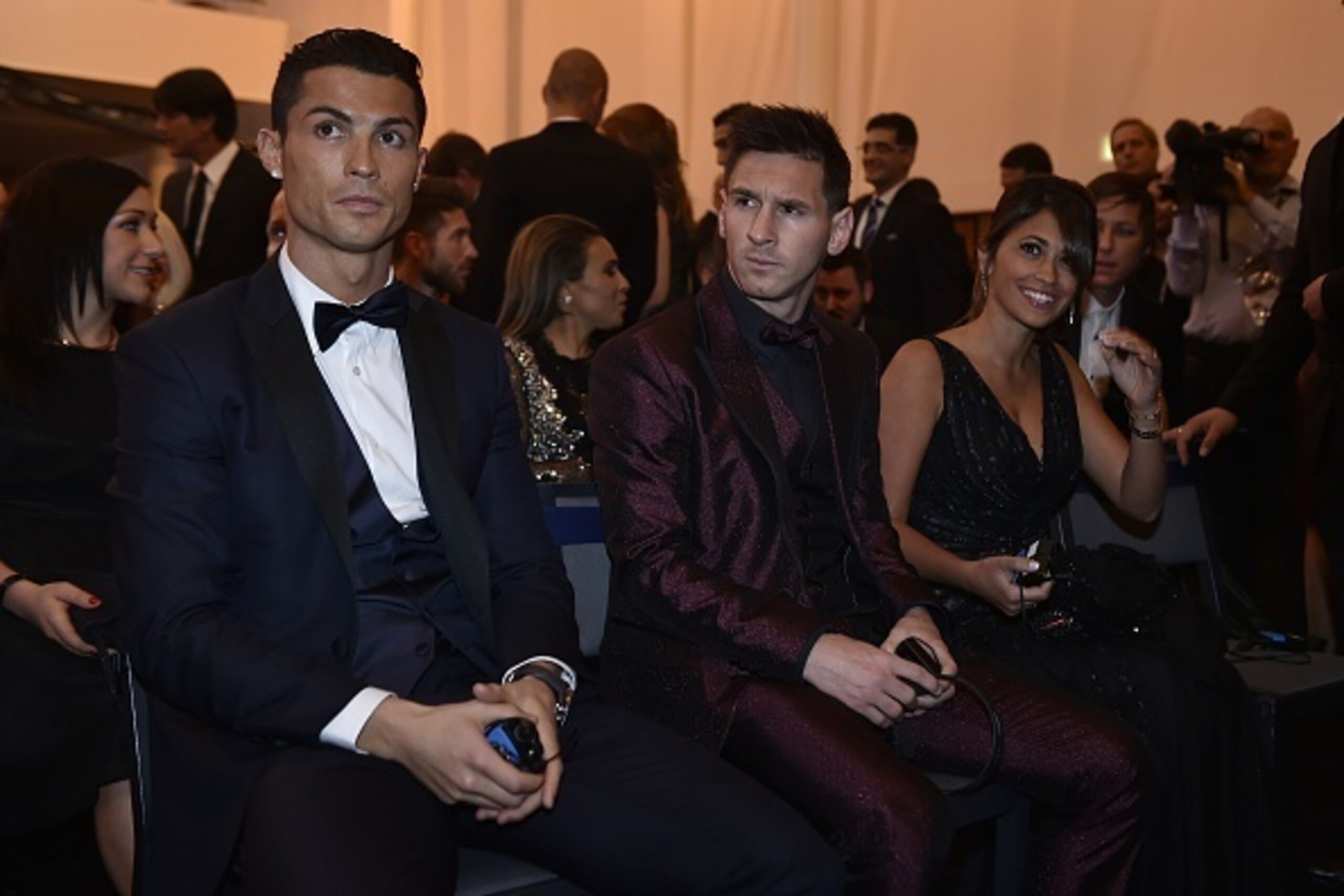 Real Madrid and Portugal forward Cristiano Ronaldo (L) sits next to Barcelona and Argentina forward Lionel Messi and his wife Argentinian model Antonella Roccuzzo as they wait for the start of the 2014 FIFA Ballon d'Or award ceremony at the Kongresshaus i