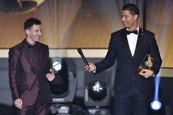 Real Madrid and Portugal forward Cristiano Ronaldo hands a microhpone to Barcelona and Argentina forward Lionel Messi (L) as they stand on stage after being selected in the 2014 FIFA FIFPro World XI during the FIFA Ballon d'Or award ceremony at the Kongre