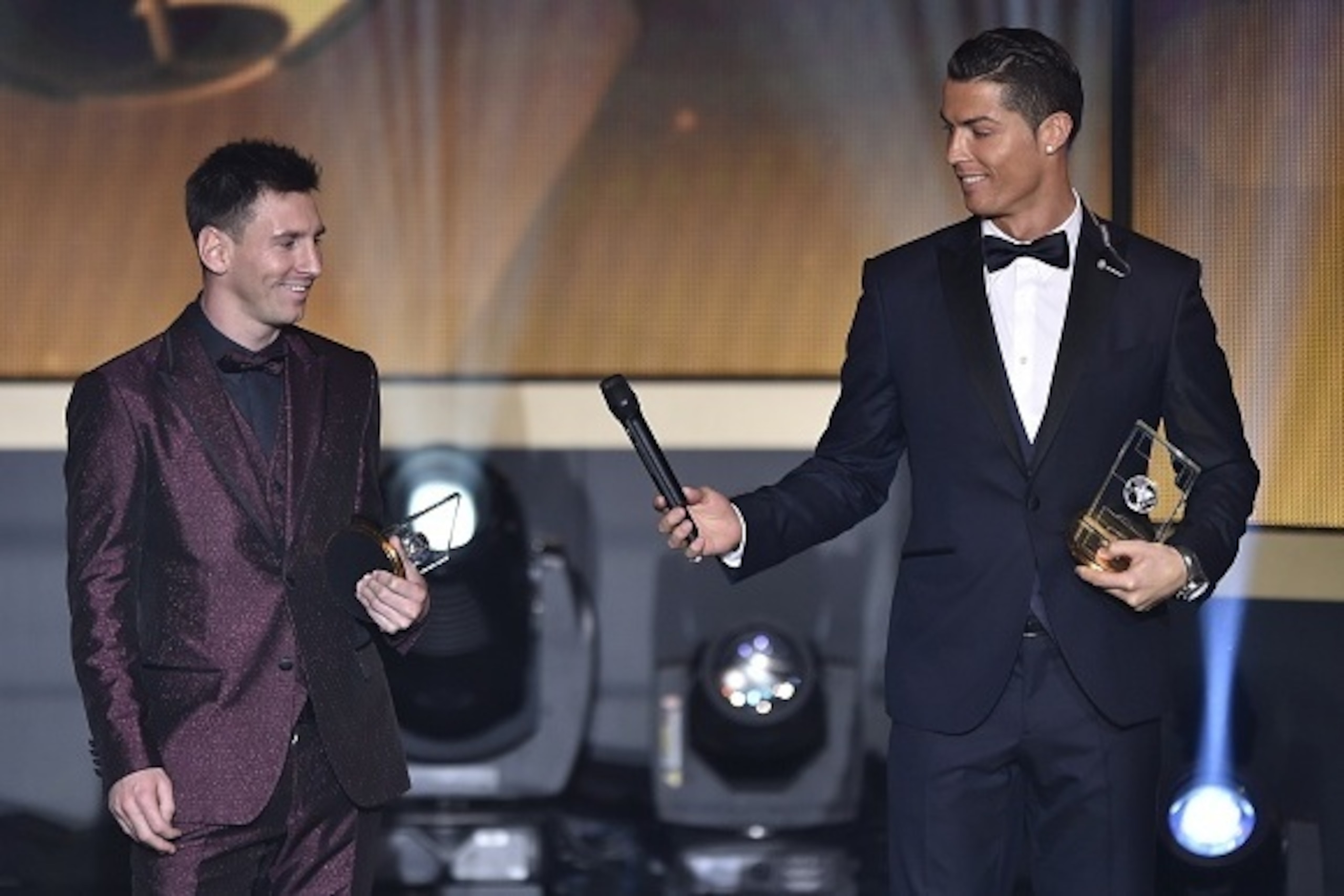 Real Madrid and Portugal forward Cristiano Ronaldo hands a microhpone to Barcelona and Argentina forward Lionel Messi (L) as they stand on stage after being selected in the 2014 FIFA FIFPro World XI during the FIFA Ballon d'Or award ceremony at the Kongre