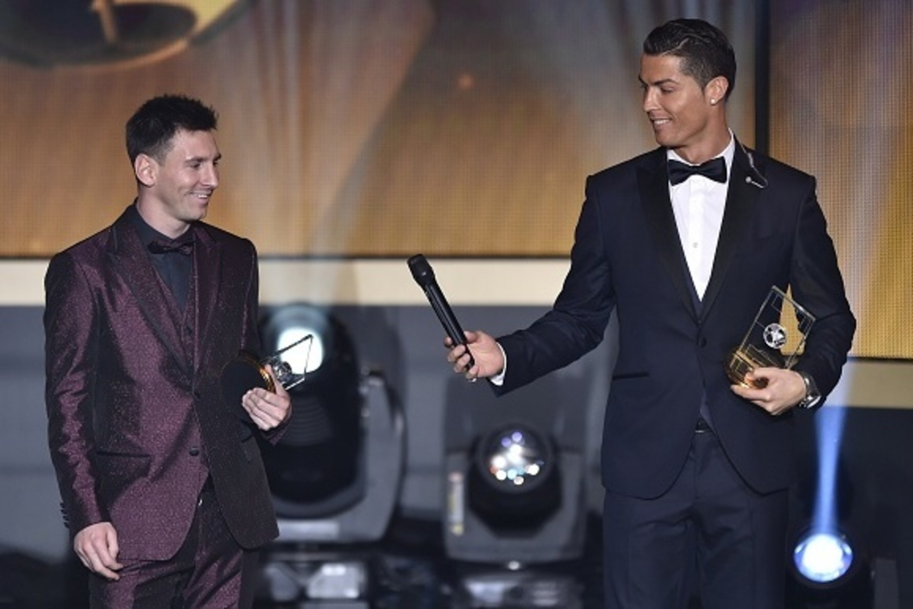 Real Madrid and Portugal forward Cristiano Ronaldo hands a microhpone to Barcelona and Argentina forward Lionel Messi (L) as they stand on stage after being selected in the 2014 FIFA FIFPro World XI during the FIFA Ballon d'Or award ceremony at the Kongre