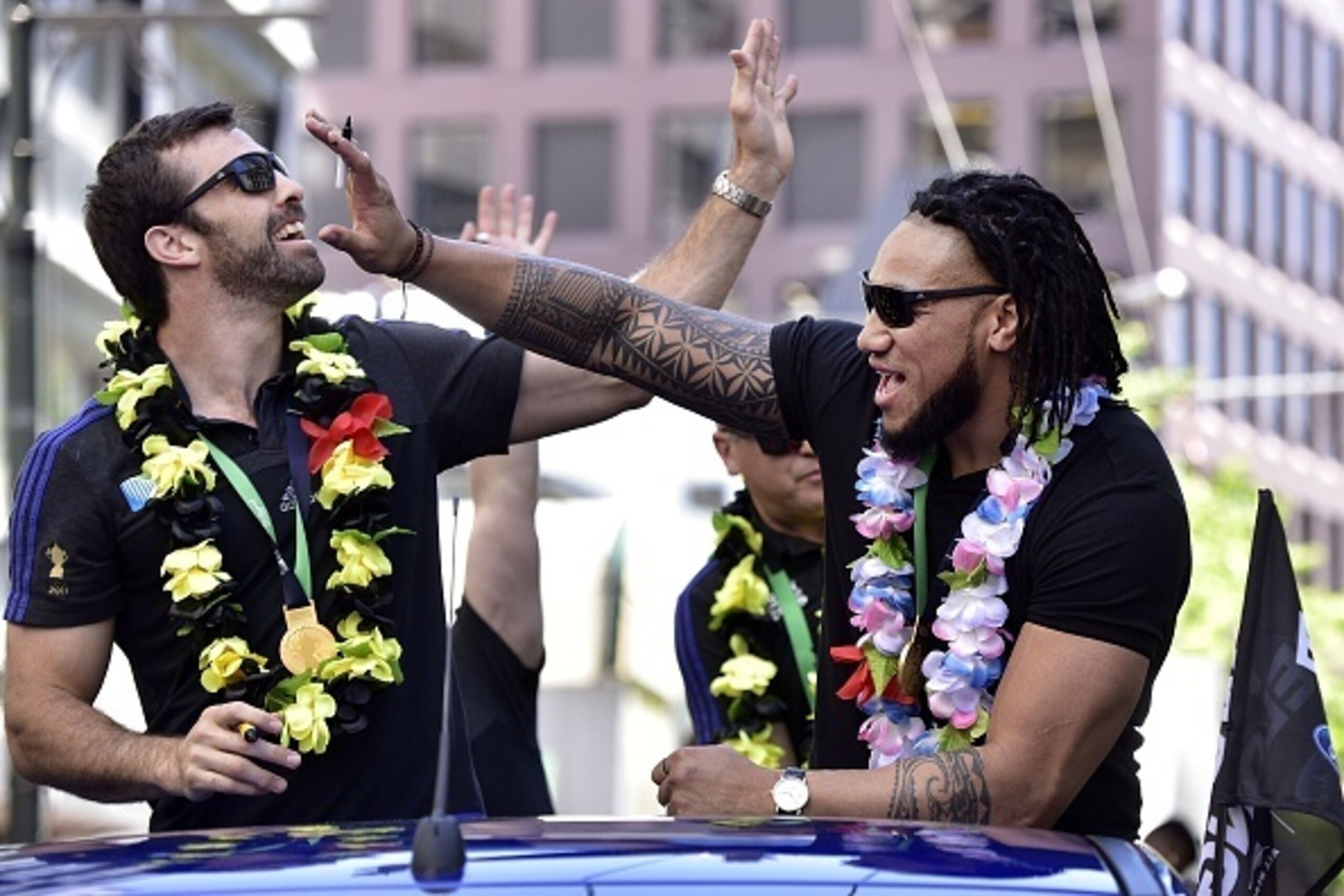 New Zealand's All Blacks rugby team players Ma'a Nonu (R) and Conrad Smith wave to fans during a parade by the team through the central business district of Wellington on November 6, 2015, following their Rugby World Cup win against Australia in England o
