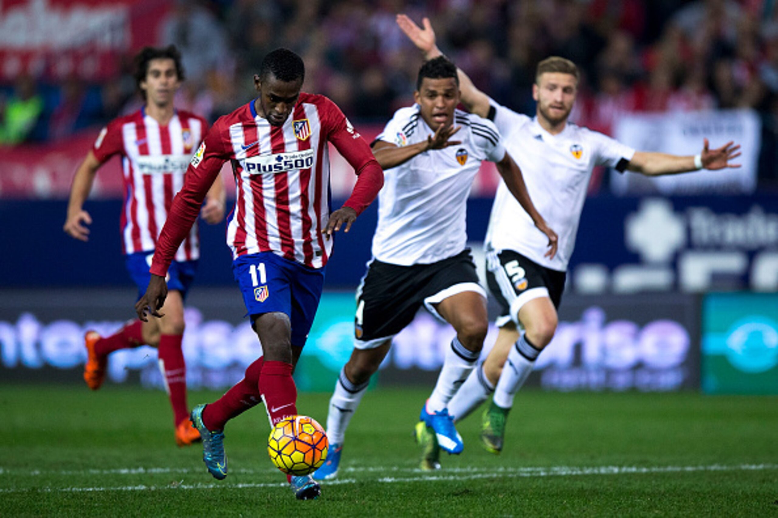 MADRID, SPAIN - OCTOBER 25: Jackson Arley Martinez (L) of Atletico de Madrid runs to score their opening goal ahead Valencia CF players Aderllan Santos (2ndR) and Shkodran Mustafi (R) during the La Liga amtch between Club Atletico de Madrid and Valencia C