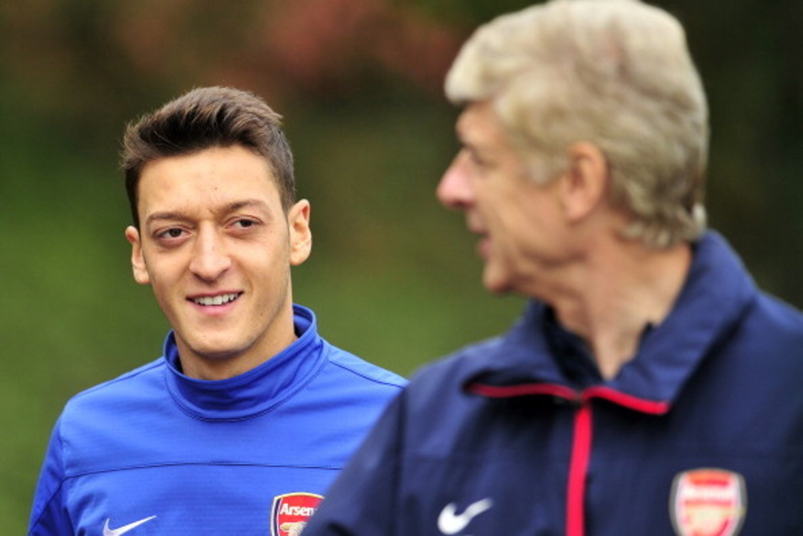 Arsenal's German midfielder Mesut Ozil (L) and French manager Arsene Wenger (R) speak during a team training session for the forthcoming UEFA Champions League Group F football match against SSC Napoli at Arsenal's London Colney training ground in north Lo