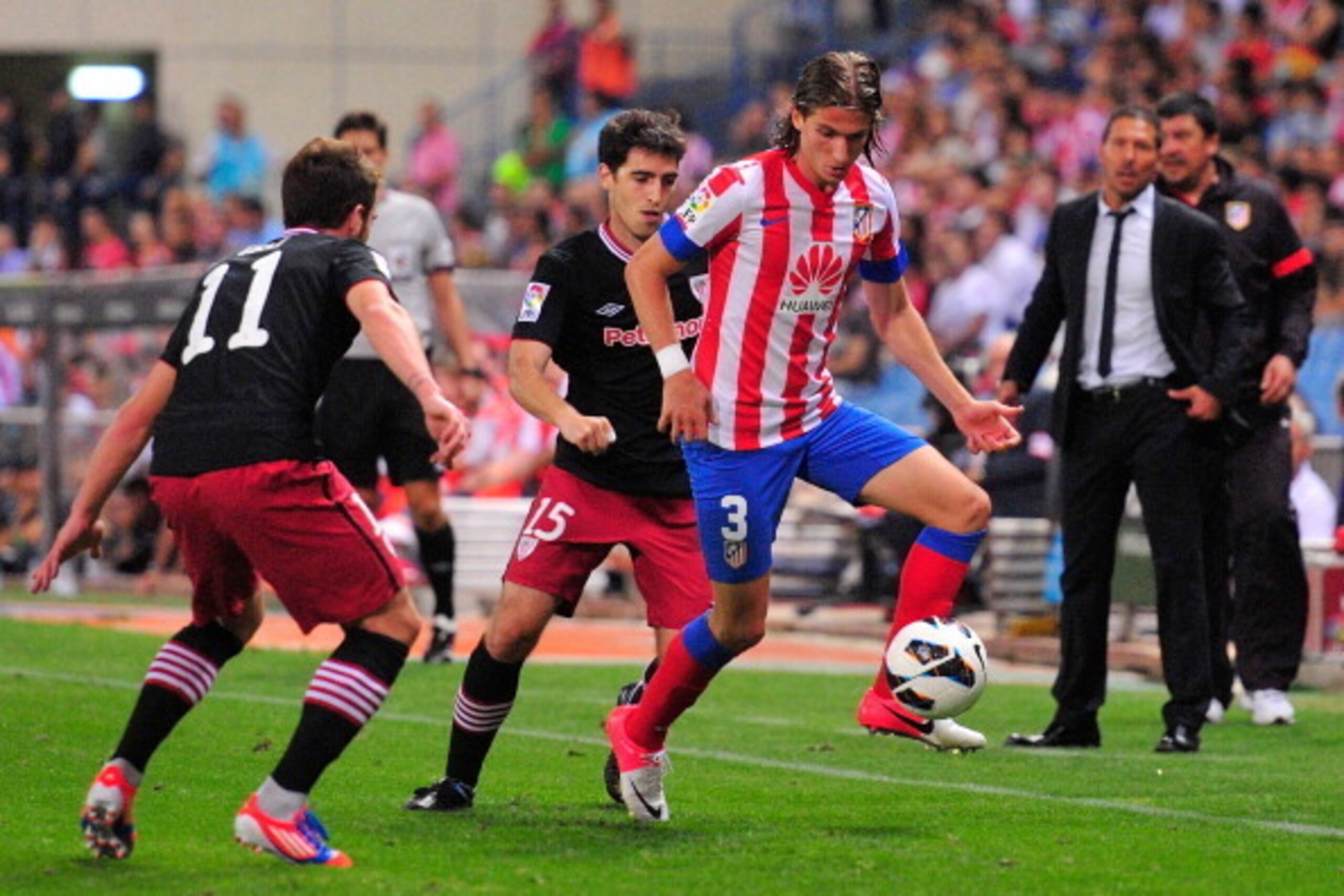 MADRID, SPAIN - AUGUST 27: Filipe Luis Kasrmirski of  Club Atletico de Madrid challenges Andoni Iraola of Athletic Club behind them head coach Diego Simeone of  Club Atletico de Madrid during the La Liga match between Club Atletico de Madrid and Athletic 