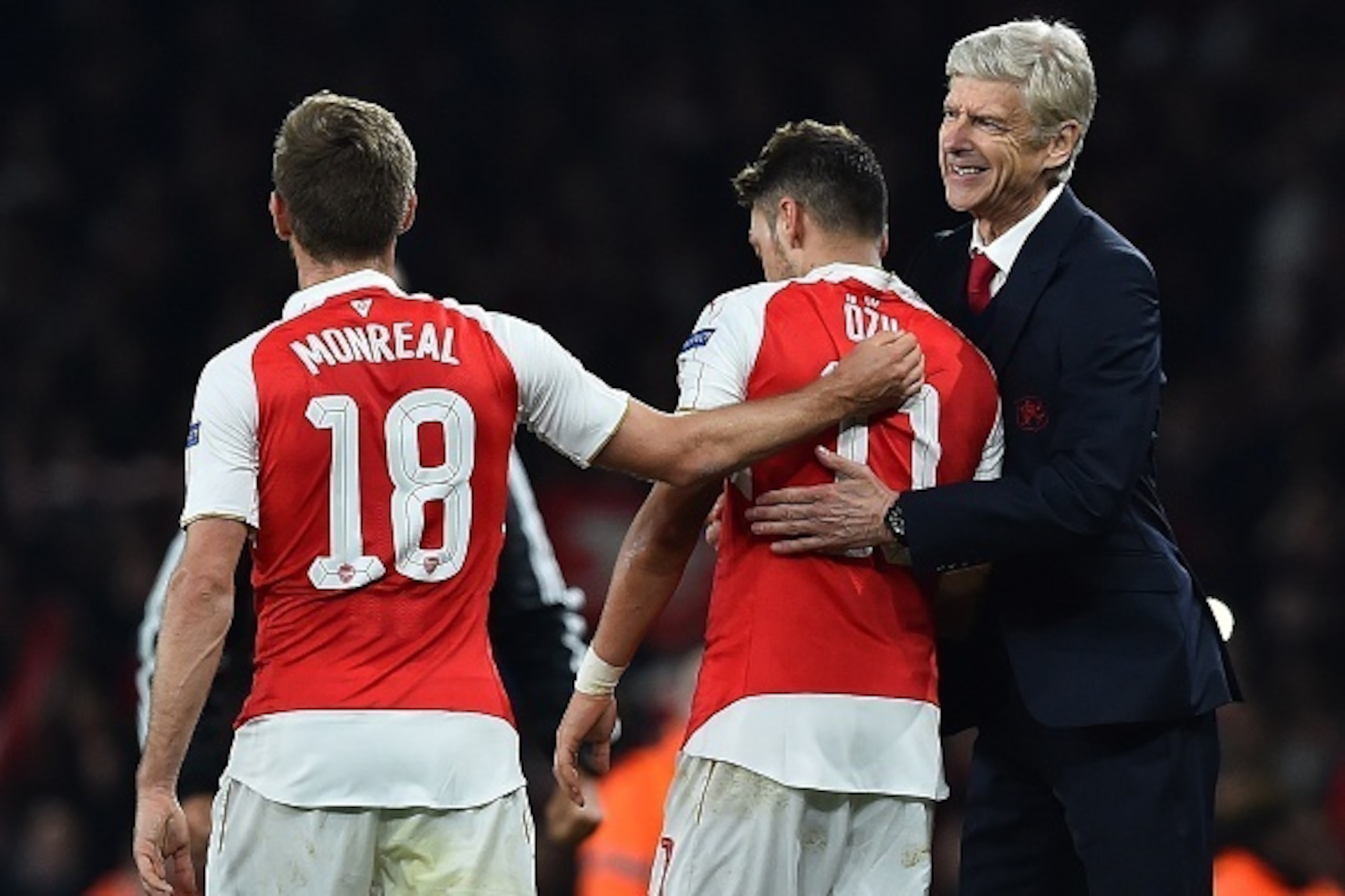 Arsenal's French manager Arsene Wenger (R) congratulates Arsenal's German midfielder Mesut Ozil (C) on scoring his team's second goal during the UEFA Champions League football match between Arsenal and Bayern Munich at the Emirates Stadium in London, on O
