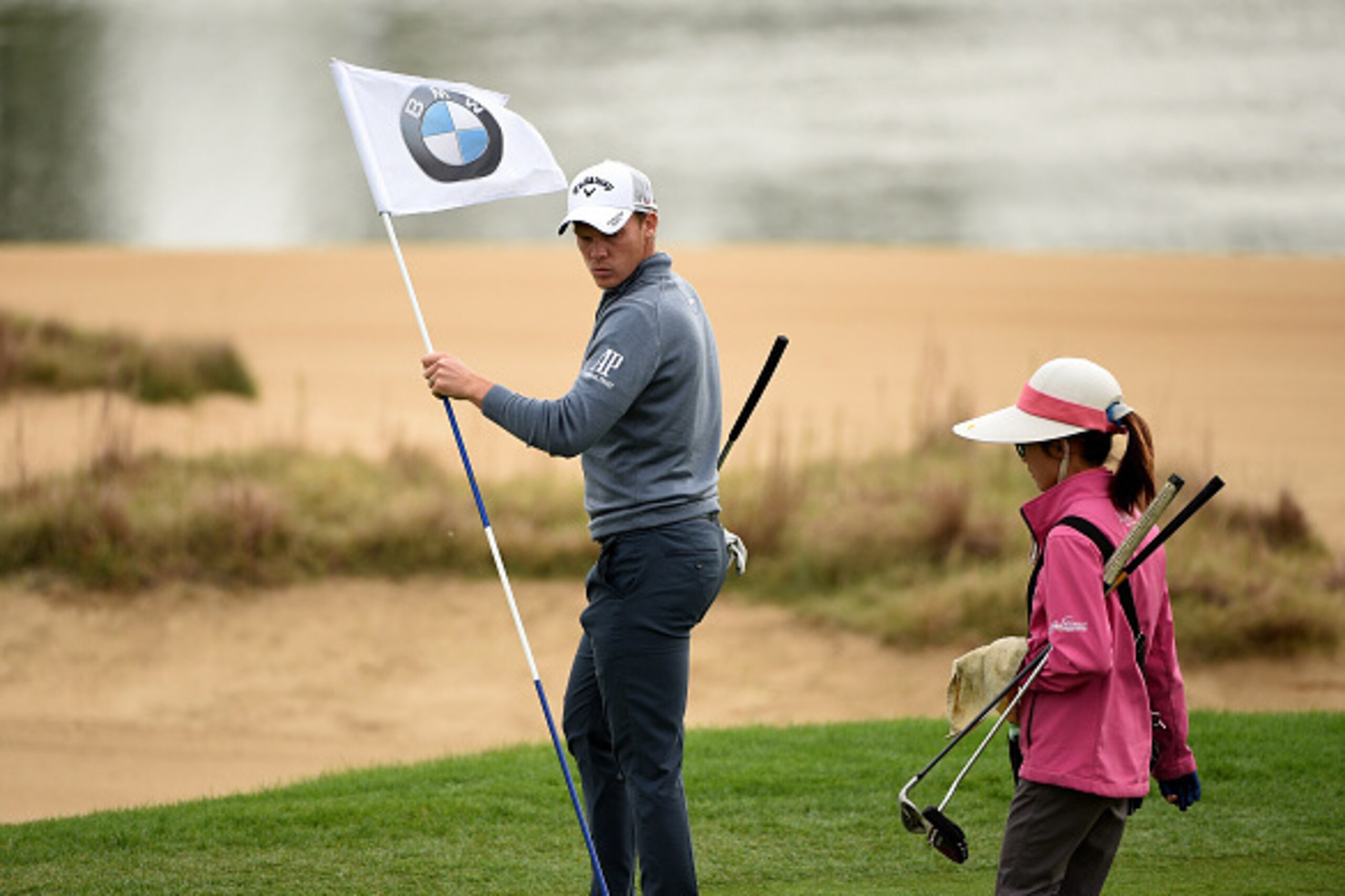 SHANGHAI, CHINA - NOVEMBER 11:  Danny Willett of England hands the pin flag to a local caddie during the pro-am event prior to the BMW Masters at Lake Malaren Golf Club on November 11, 2015 in Shanghai, China.  (Photo by Ross Kinnaird/Getty Images)